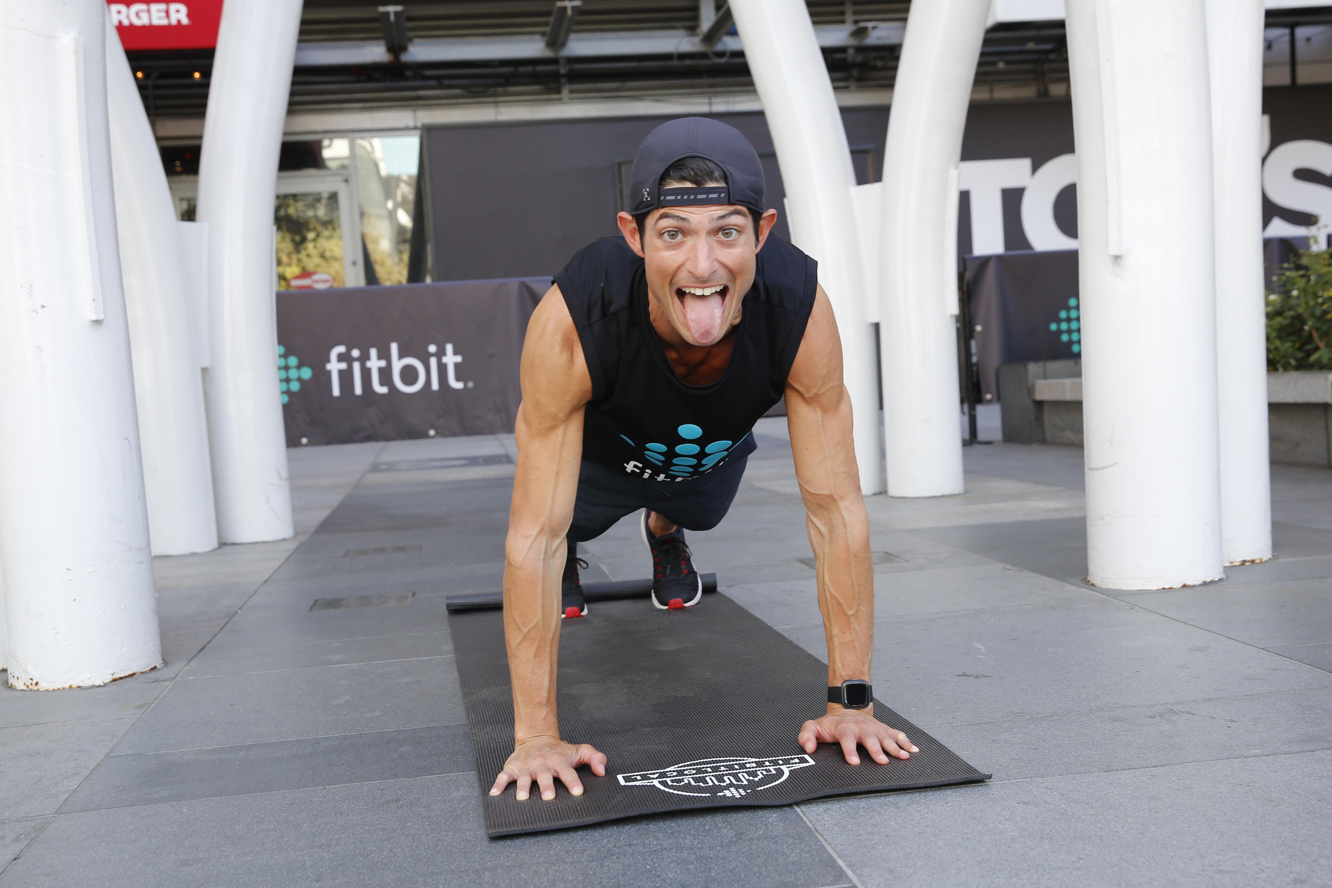 A man sticks his tongue out while doing a plank.