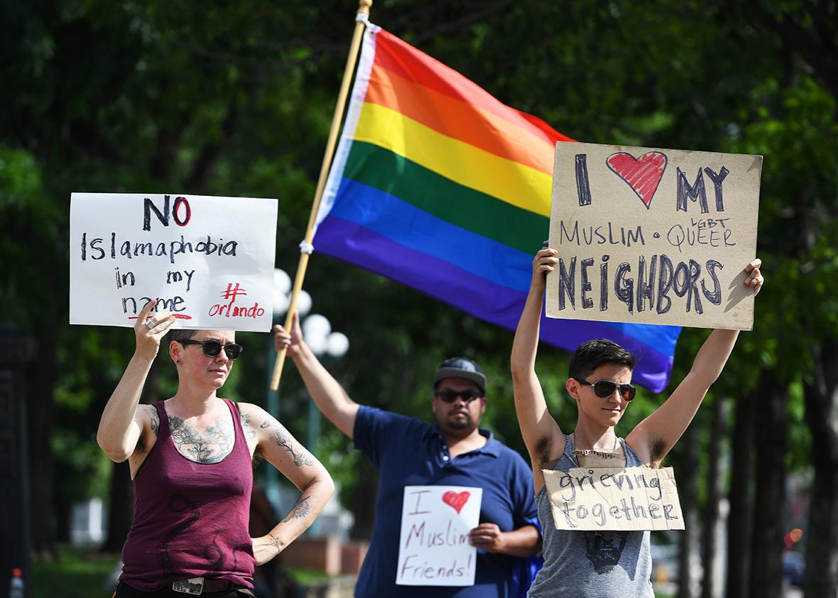 Lynne Sprague, left, Jeremy Bermudez, in back in middle, and Andy Coco, right,  who are all part of the Denver LGBTQ community, show their support for the muslim community  at the corners of Broadway and Colfax on June 12, 2016  in Denver, Colorado. 