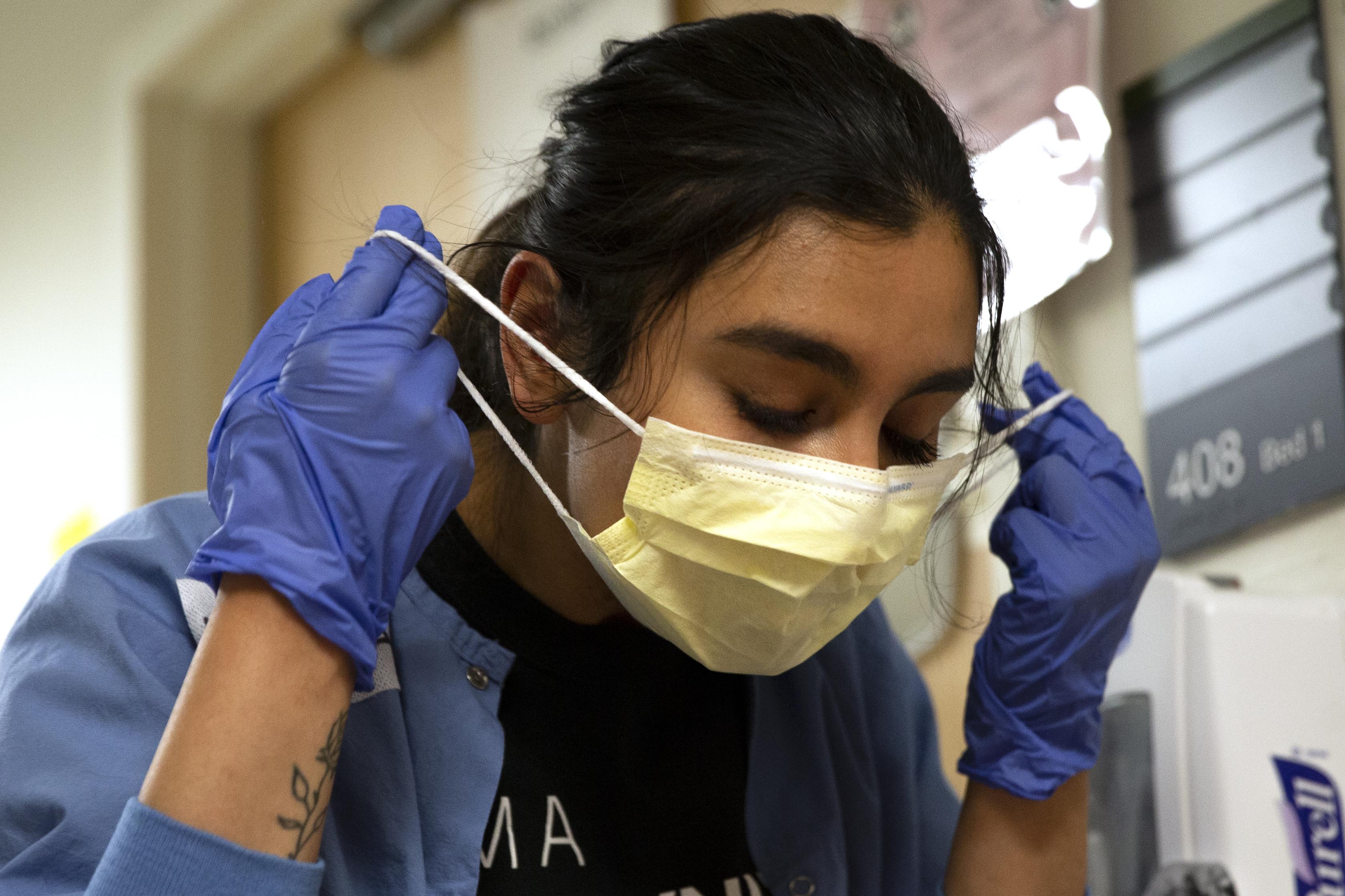 Charge nurse Liliana Palacios carefully removes her mask and PPE after tending to a patient with COVID-19 in the acute care COVID unit at Harborview Medical Center on May 7, 2020 in Seattle, Washington. 