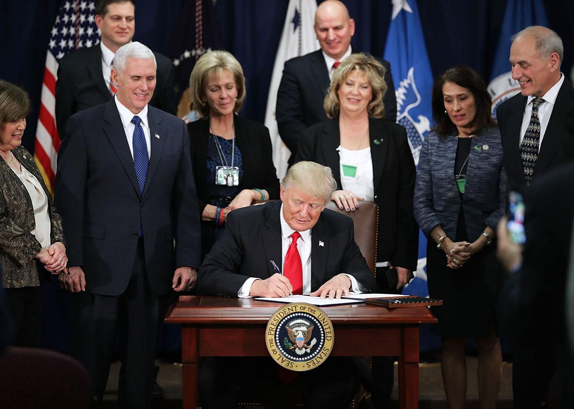 U.S. President Donald Trump signs four executive orders during a visit to the Department of Homeland Security with Vice President Mike Pence, Homeland Security Secretary John Kelly and other officials January 25, 2017 in Washington, DC. 