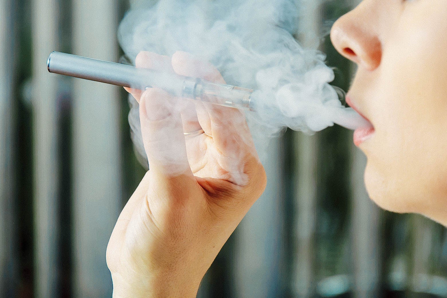 Stock photo of a girl smokes an electronic cigarette and exhaling flavored steam.