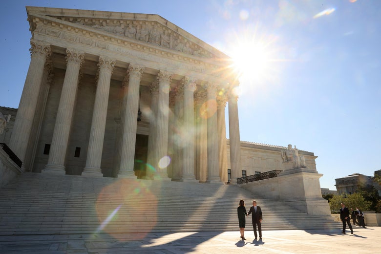 The sun shines over the Supreme Court as Amy Coney Barrett and John Roberts shake hands on its gleaming white plaza.
