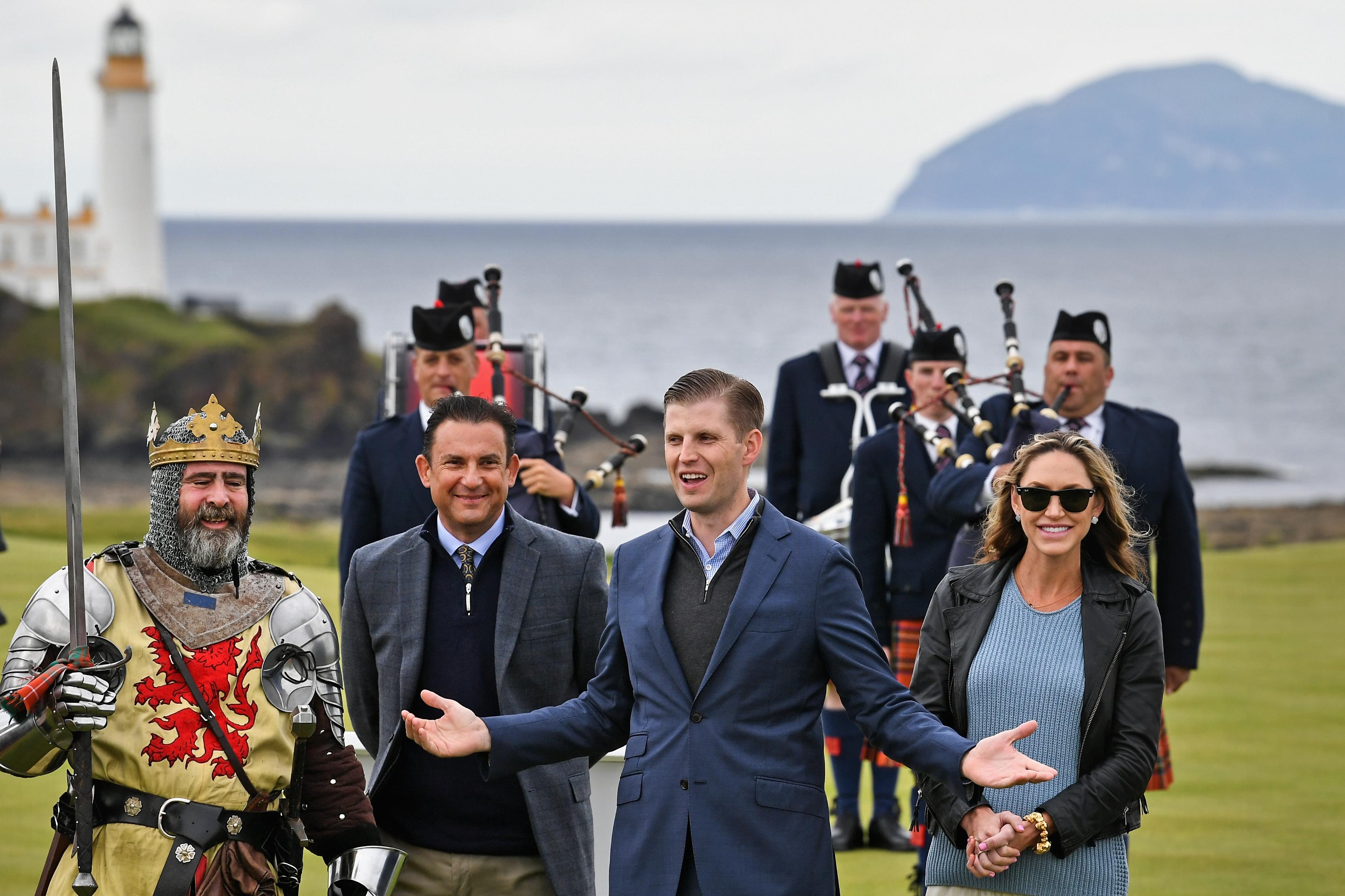 Eric Trump and his wife, Lara, at Turnberry golf course, surrounded by a man dressed as a knight and other men in kilts.