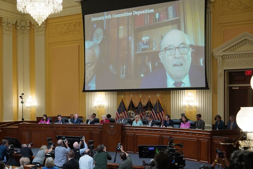 A photo of Monday’s Jan. 6 select committee hearing at the Capitol that shows Rudy Giuliani on a big screen in front of Congresspeople.