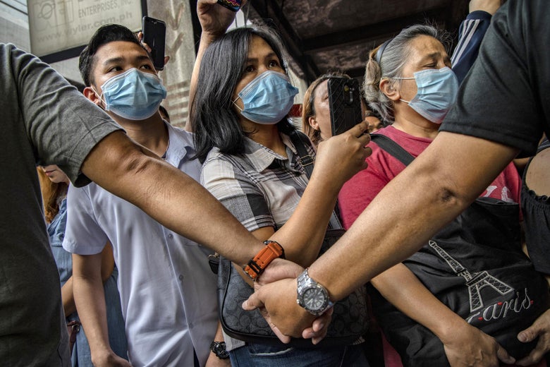 Police officers stand guard as Filipinos hoping to buy face masks crowd outside a medical supply shop that was raided by police for allegedly hoarding and overpricing the masks, as public fear over China's Wuhan Coronavirus grows, on January 31, 2020 in Manila, Philippines. 