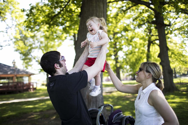 Patrick lifts his daughter, Clementine, at a park as Celeste watches.
