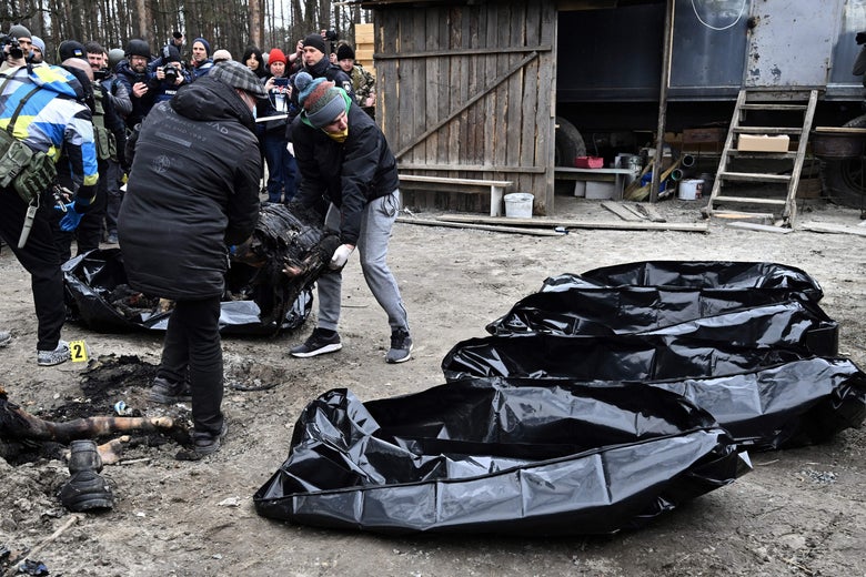 EDITORS NOTE: Graphic content / Policemen and city workers carry six partially burnt bodies into body bags as reporters attend in the town of Bucha on April 5, 2022, as Ukrainian officials say over 400 civilian bodies have been recovered from the wider Kyiv region, many of which were buried in mass graves. - Bucha had been occupied by Russian troops, but when they withdrew recently Ukrainian authorities and independent international journalists including AFP found bodies of people in civilian clothing, some with their hands tied behind their backs. (Photo by Genya SAVILOV / AFP) (Photo by GENYA SAVILOV/AFP via Getty Images)