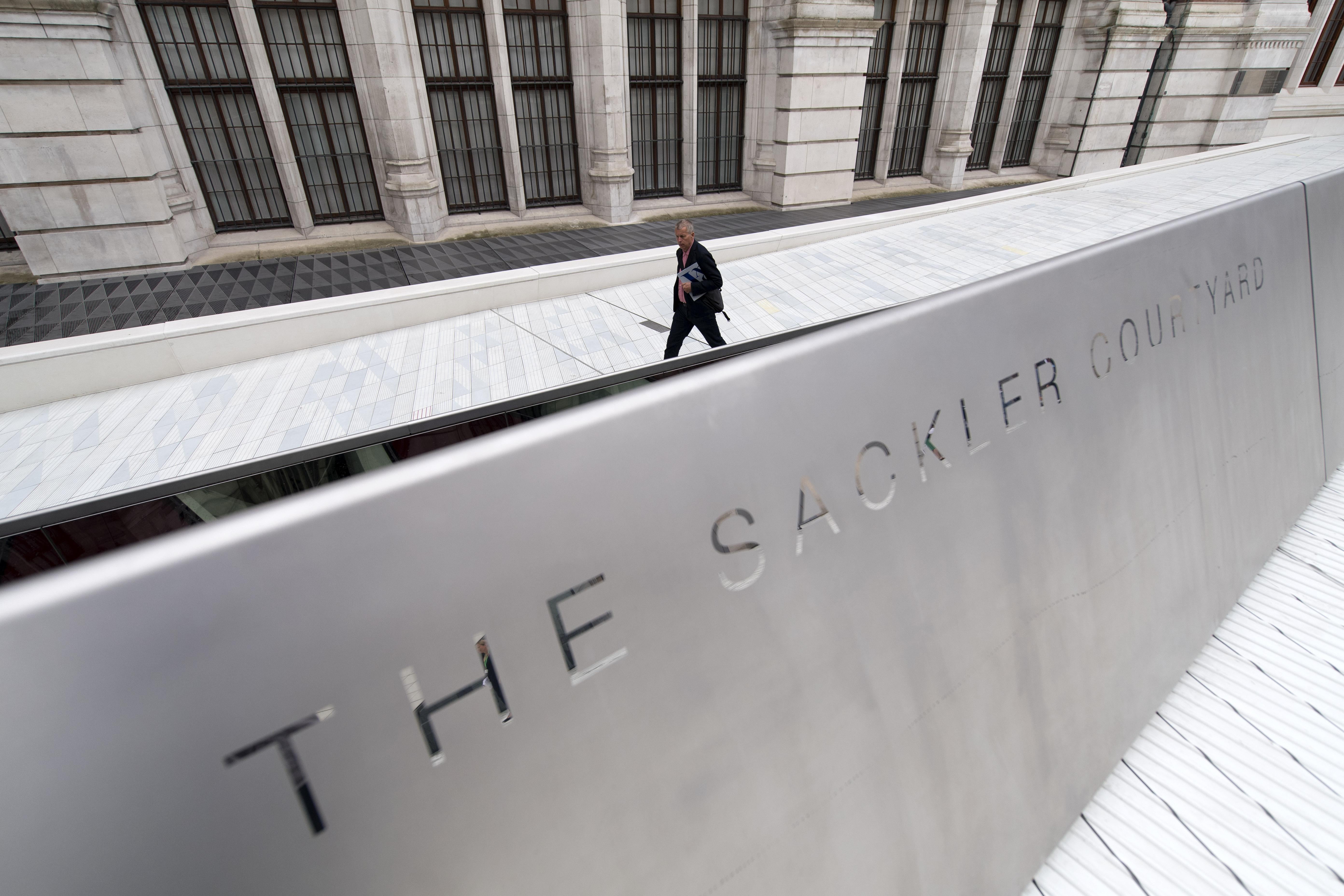The words "The Sackler Courtyard" can be seen on a low wall in front of white plaza. 