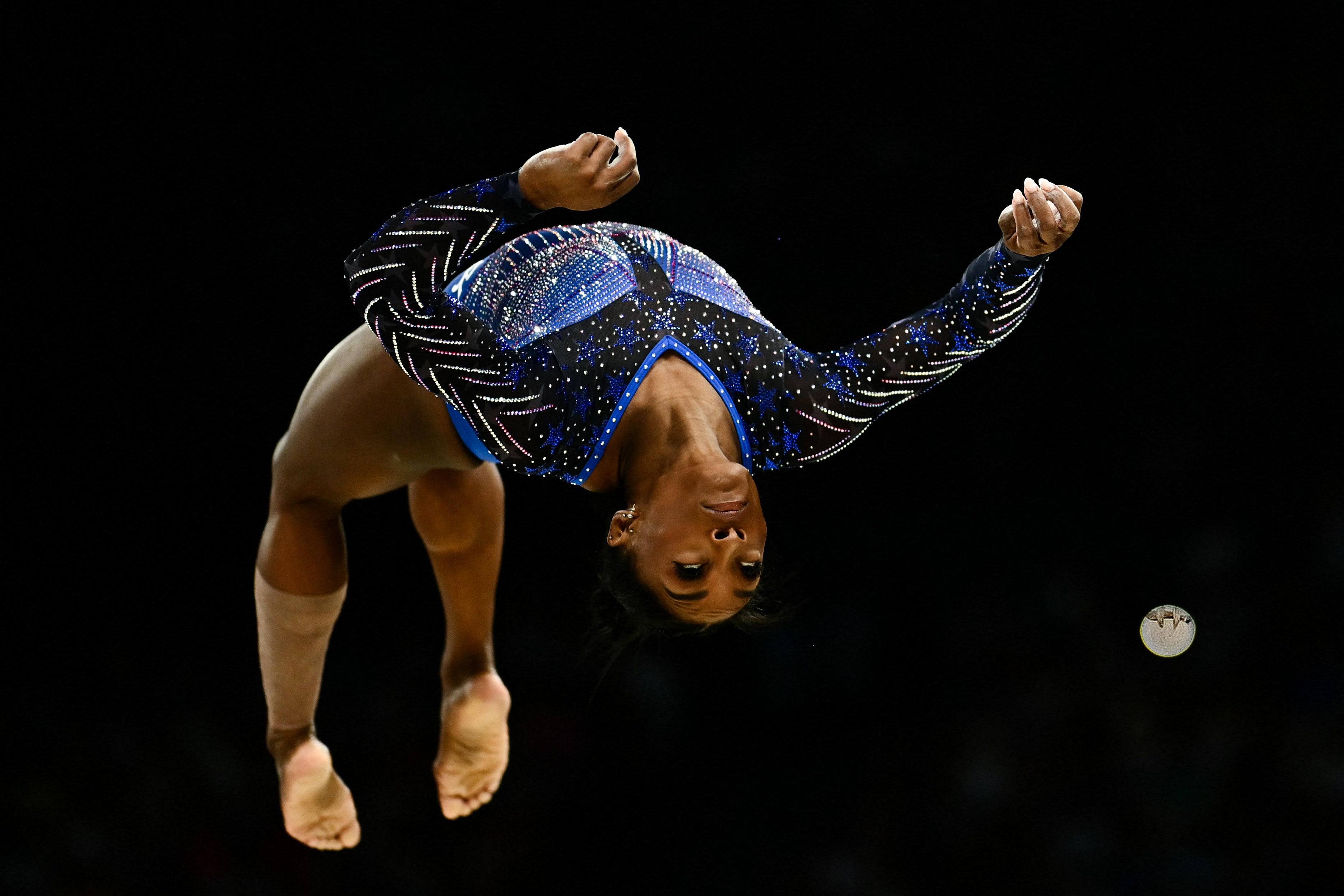 Biles upside down, arching her back as she flips midair.