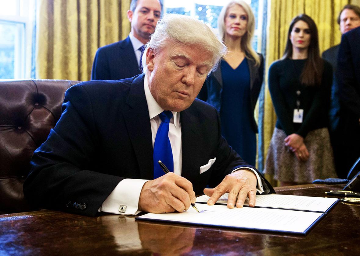 US President Donald Trump signs an executive order in the Oval Offoice at the White House in Washington, DC, on January 24, 2017.