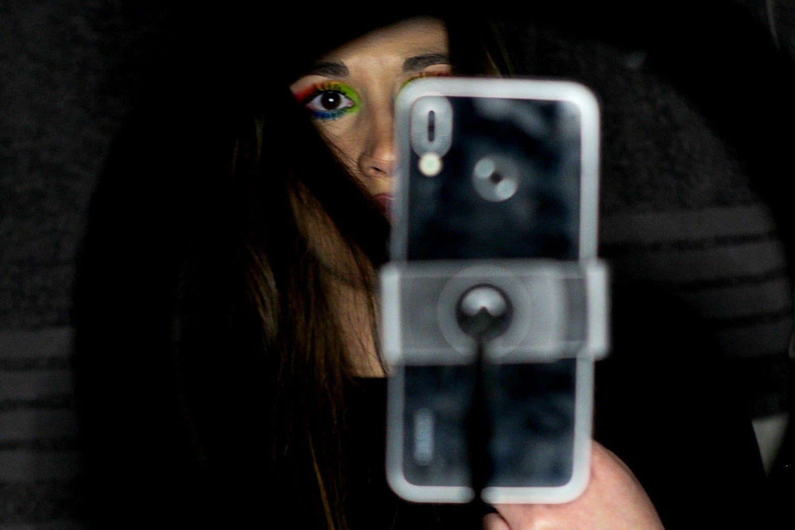 A person partially visible behind a smartphone on a stand.