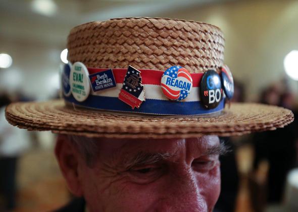 Hank Schwab shows off the campaign hat he’s worn for the past 30 years at a gathering in support of Republican U.S. Senate candidate David Perdue on Nov. 4, 2014, in Atlanta