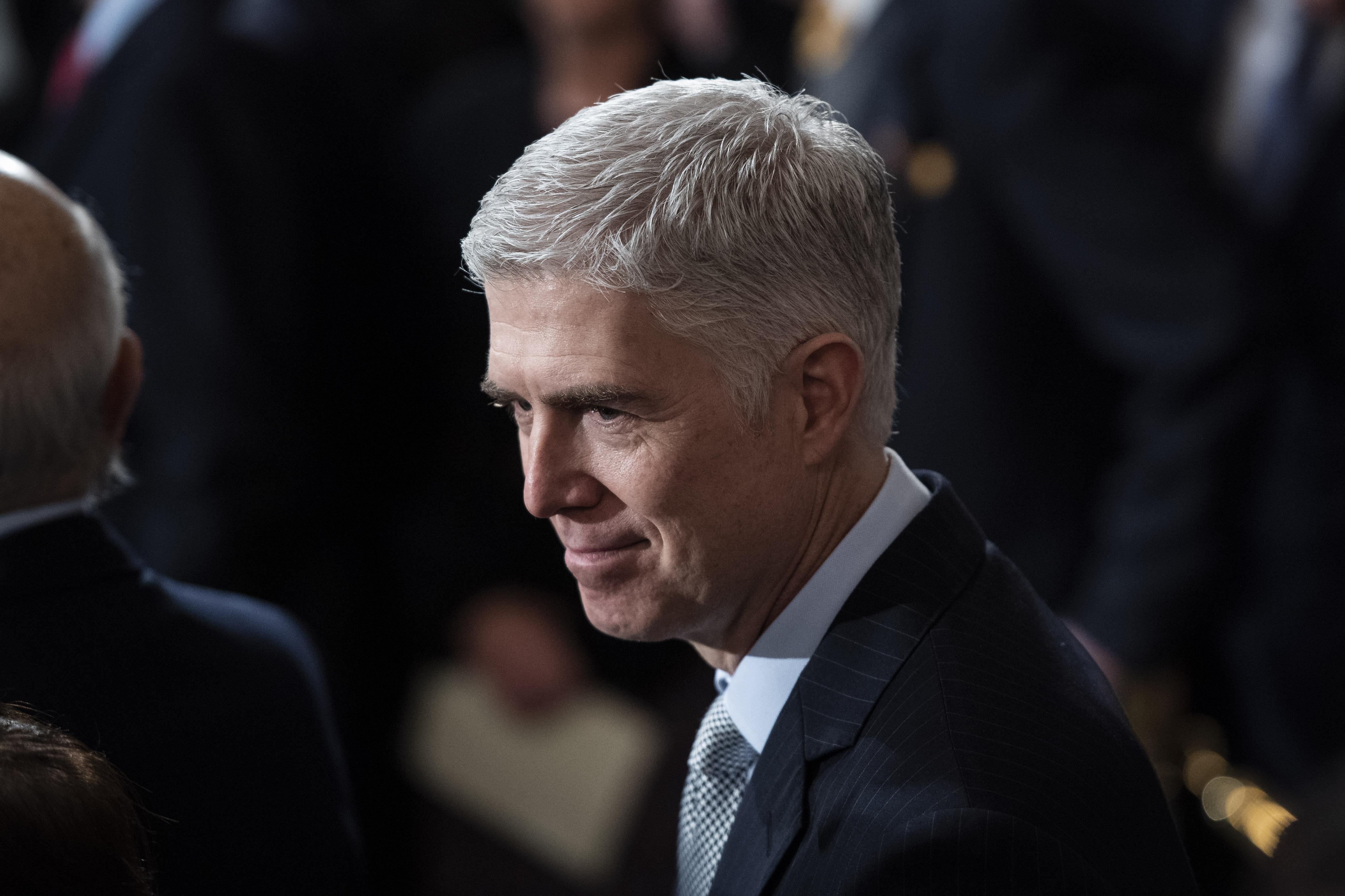 Gorsuch standing in a crowd smiling in a suit