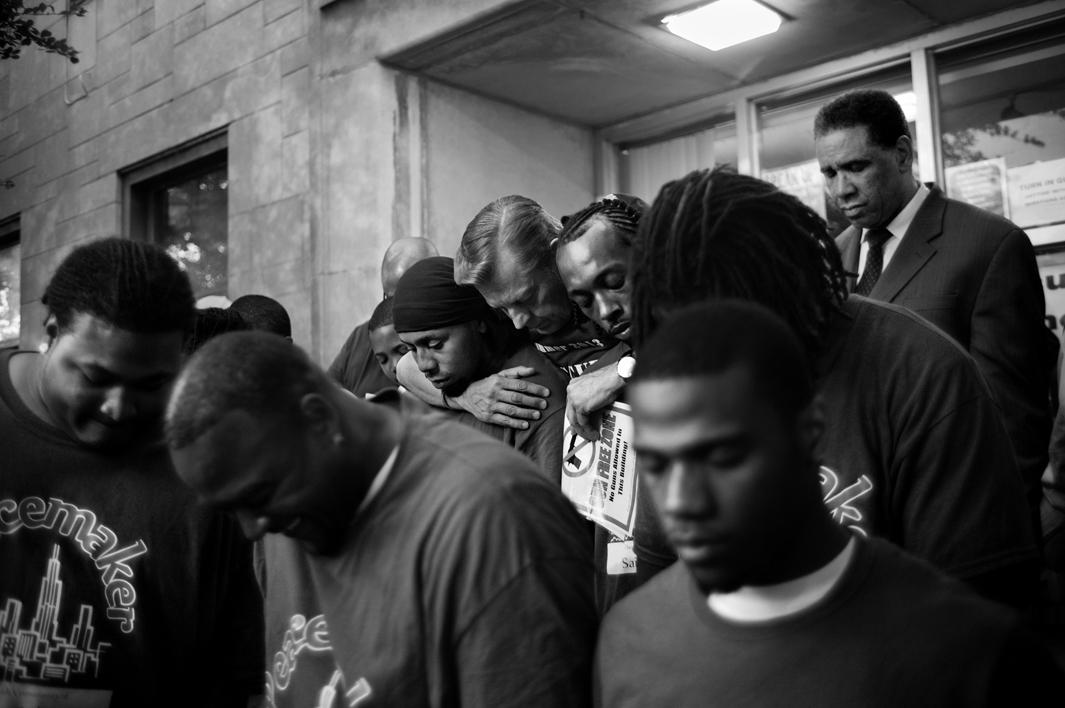 PG 128-129: Father Mike of St. Sabina Church hugs young men who work to break the cycle of violence during a prayer service. Auburn Gresham, Chicago, 2013