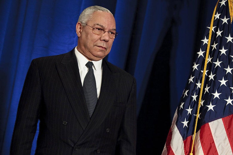 Colin Powell standing next to an American flag.