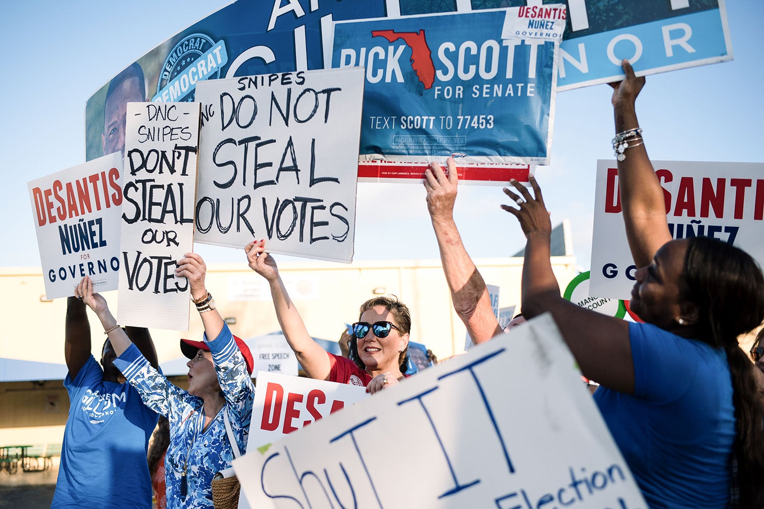 Various protesters hold up signs in support of Ron DeSantis, Rick Scott, and Andrew Gillum.