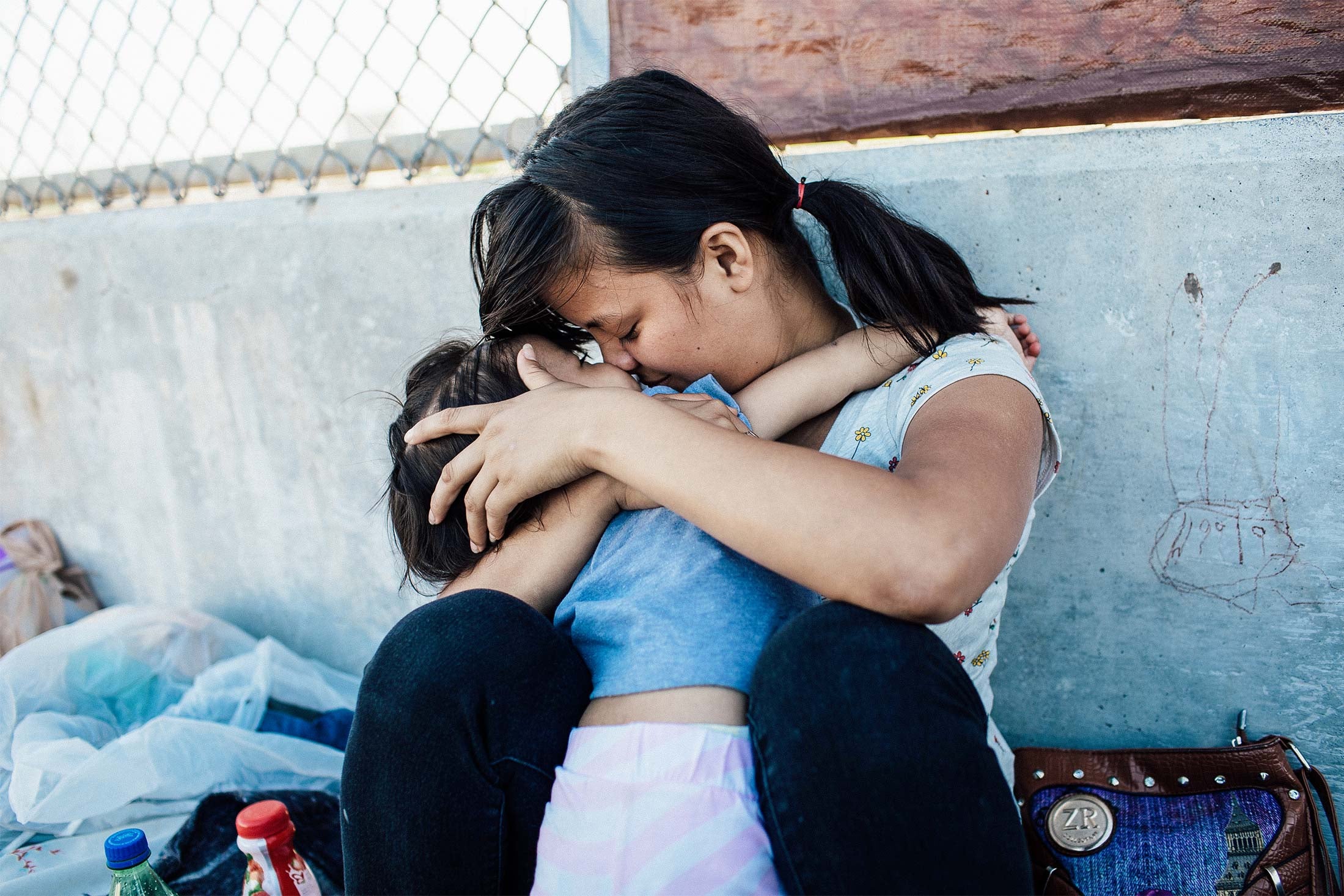 A Honduran woman embraces her 2-year-old daughter as they wait on the Mexican side of the Brownsville & Matamoros International Bridge.
