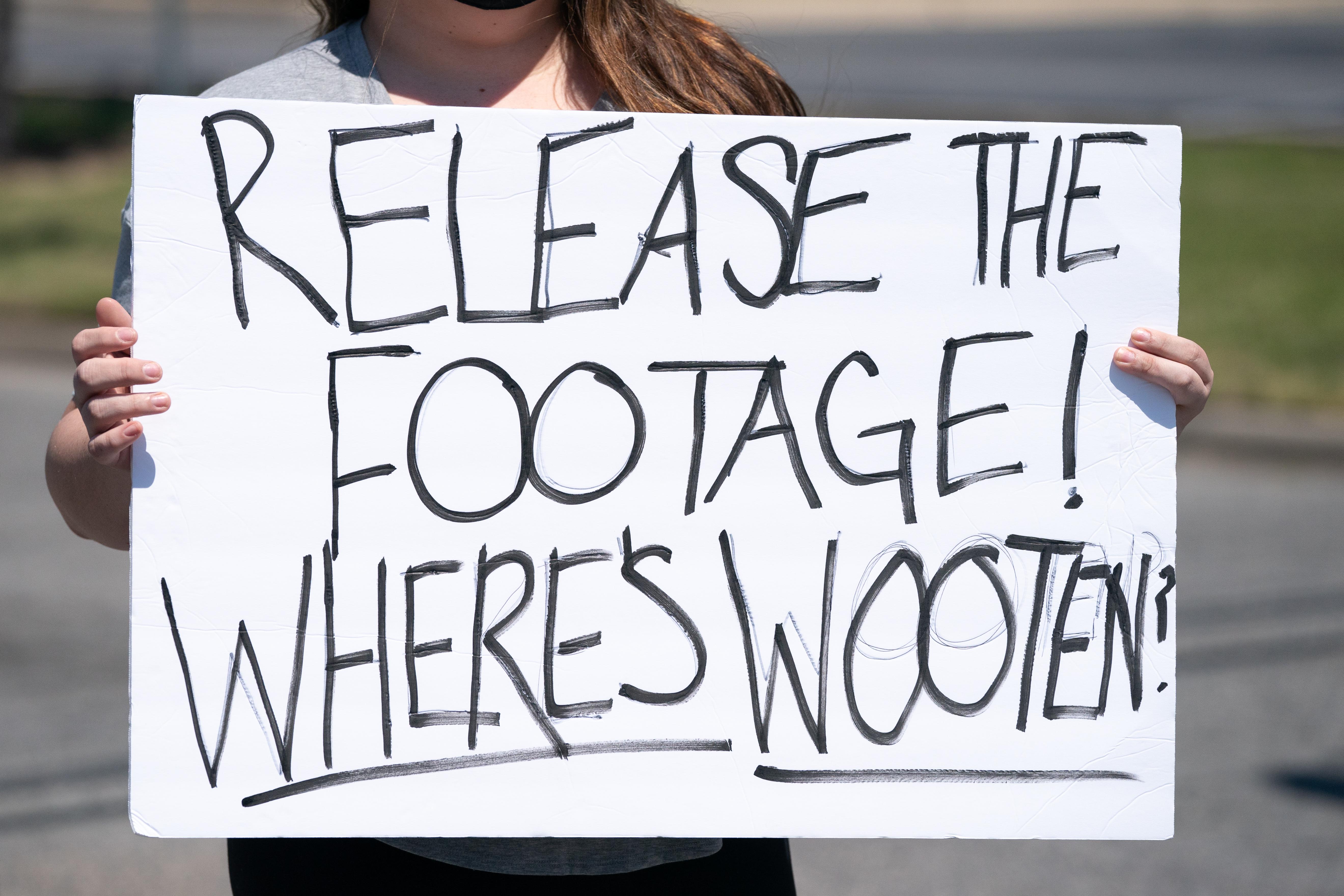 A demonstrator holds a sign addressing Pasquotank County Sheriff Tommy Wooten after an emergency city council meeting April 23, 2021 in Elizabeth City, North Carolina. 