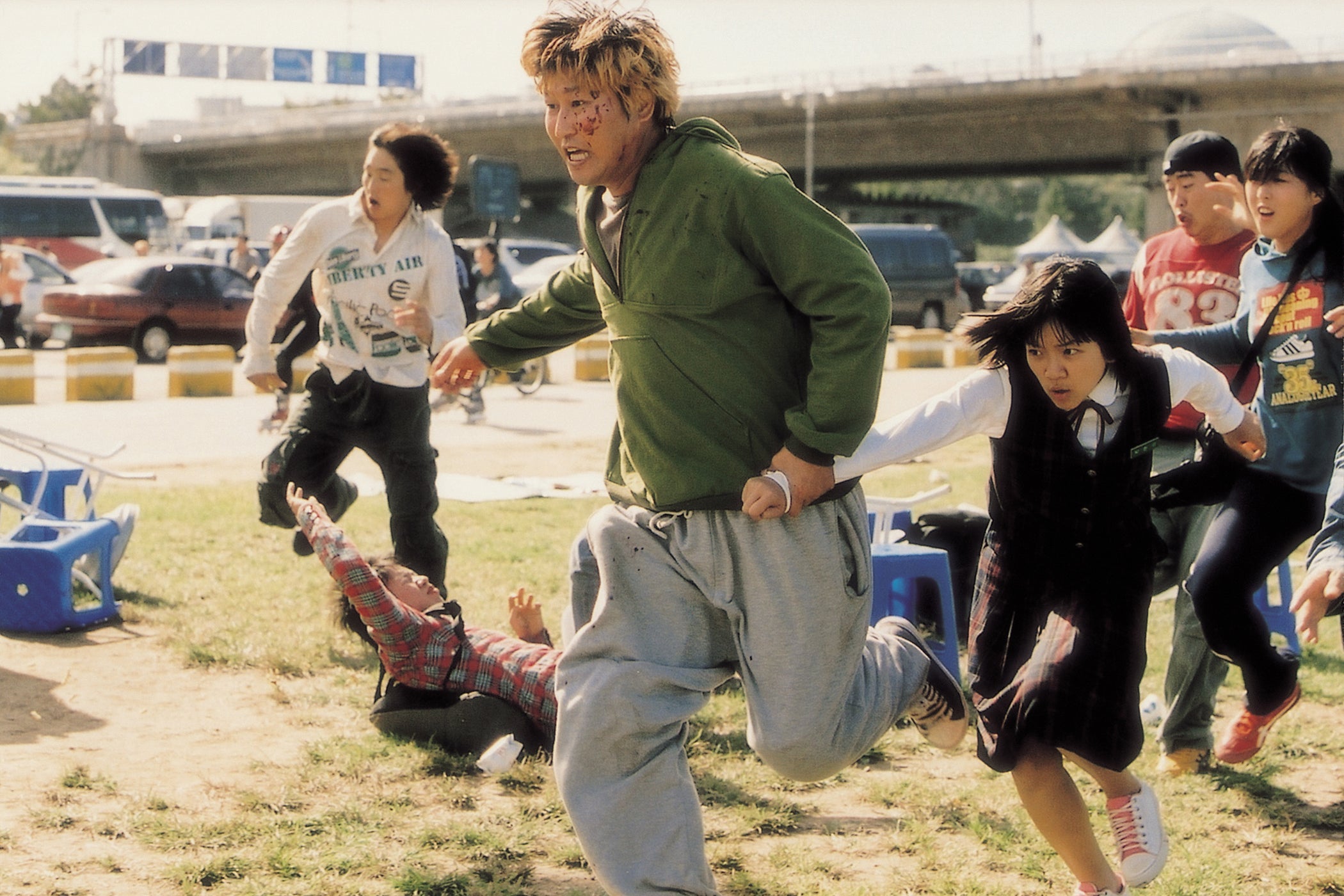 In a scene from The Host, Song Kang-ho, Ko A-sung, and others flee, running in front of a parking lot.