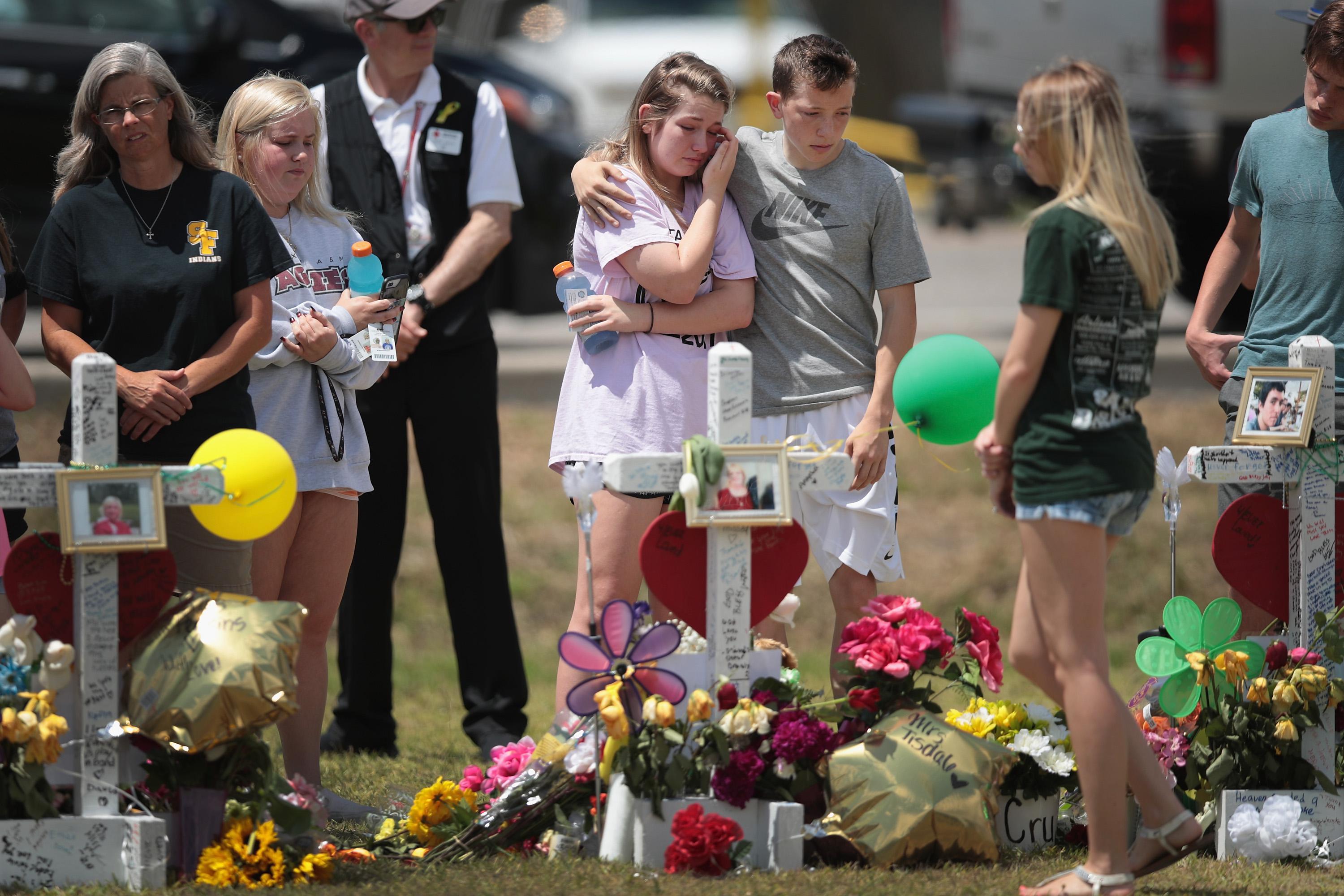 SANTA FE , TX - MAY 22:  Mourners visit a memorial in front of Santa Fe High School on May 22, 2018 in Santa Fe, Texas. The makeshift memorial honors the victims of last Friday's shooting when 17-year-old student Dimitrios Pagourtzis entered the school with a shotgun and a pistol and opened fire, killing 10 people.  (Photo by Scott Olson/Getty Images)