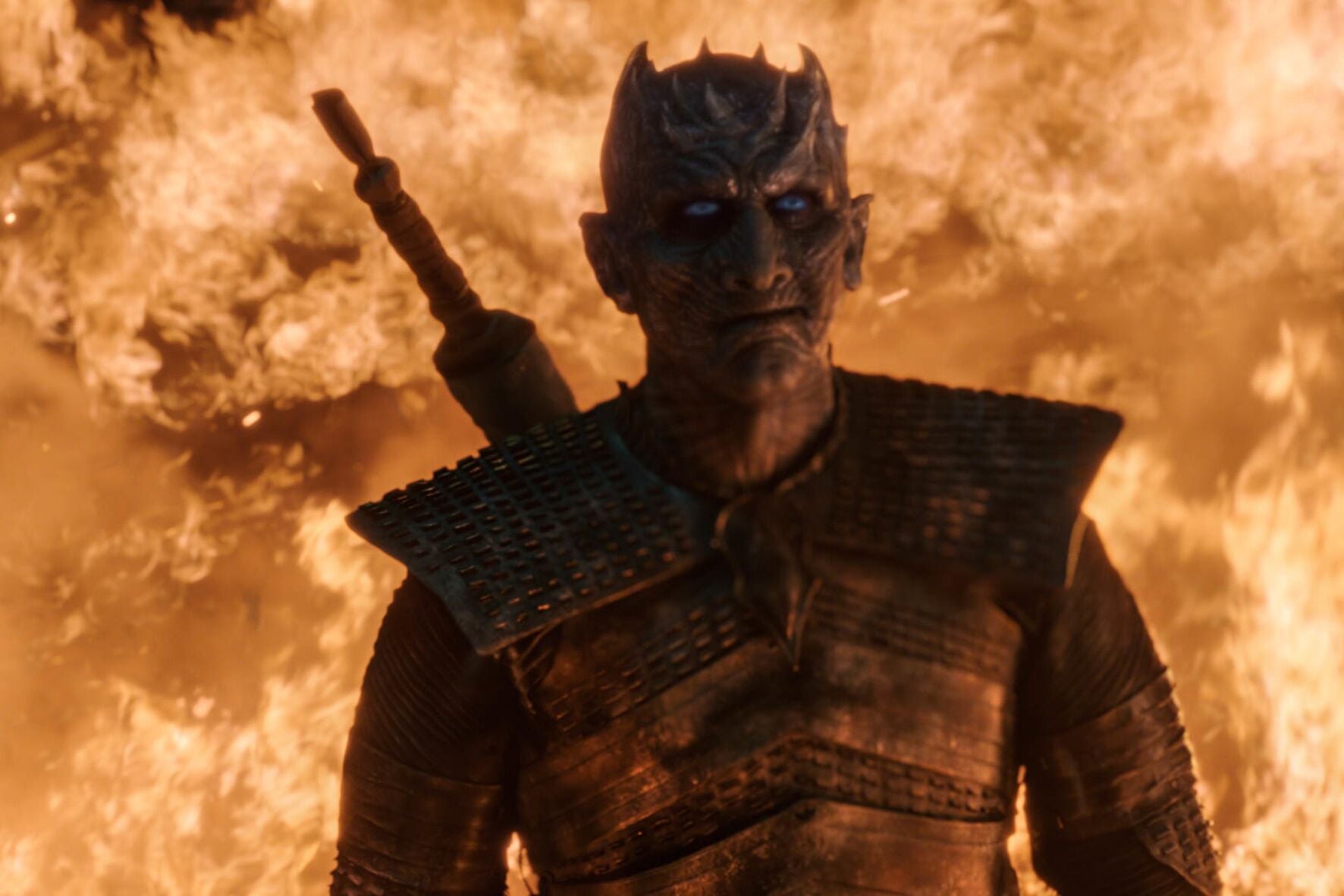 The Night King stands before a wall of fire, with a smirk on his face.