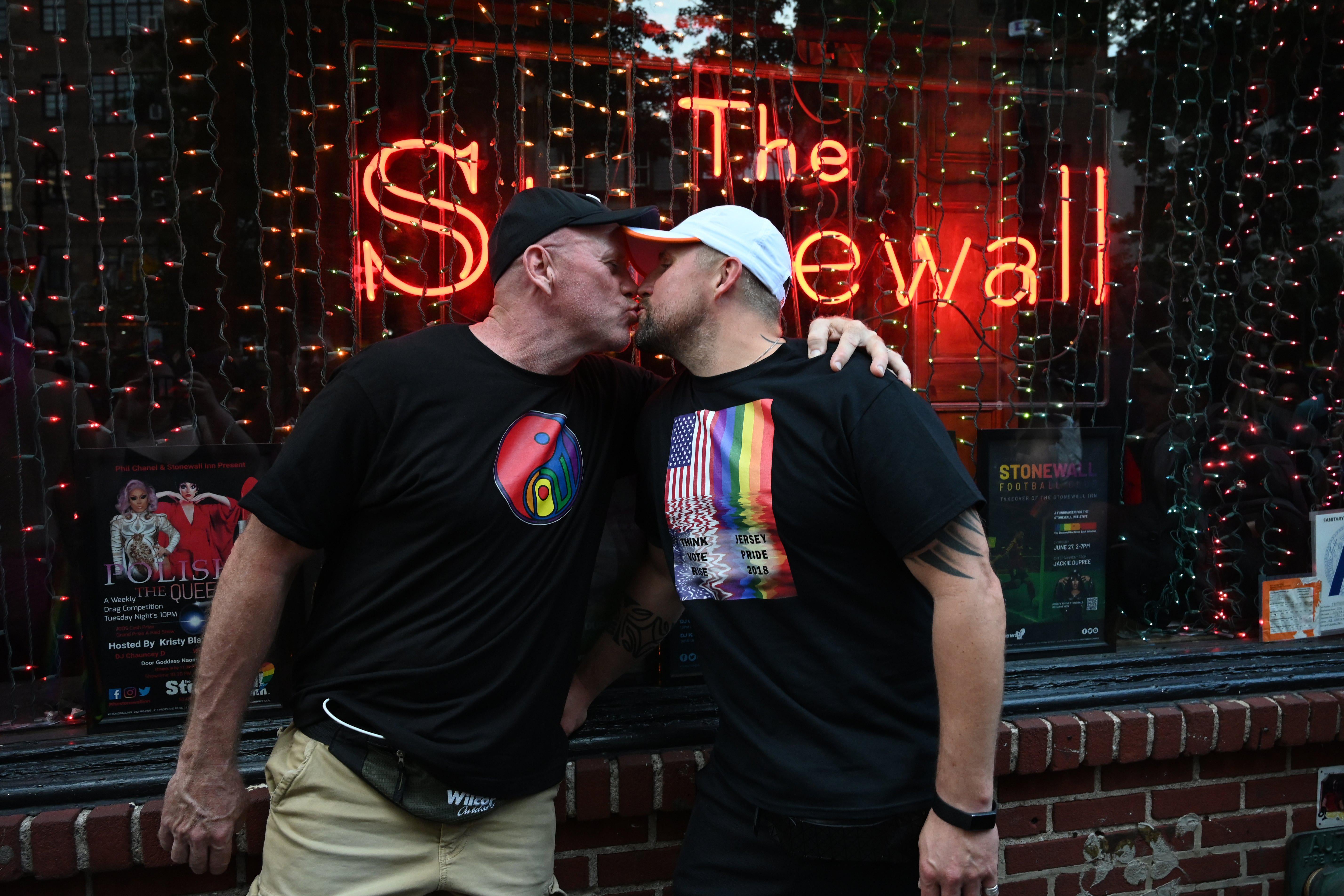 Two people kiss in front of the Stonewall Inn bar during Pride celebrations.