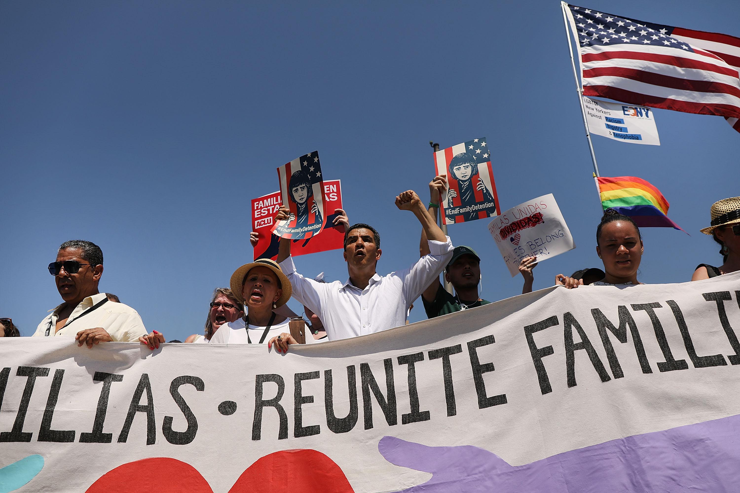 Protesters march with a banner that says "Reunite Families."