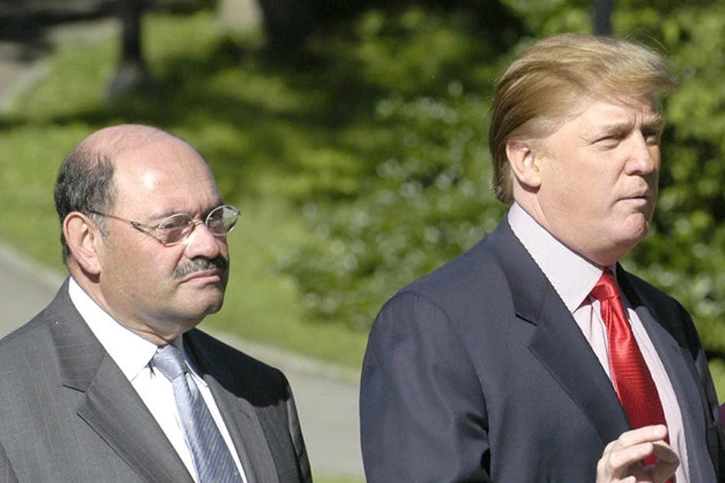 Weisselberg, a shorter bald man with a mustache, stands next to Trump while Trump gestures.