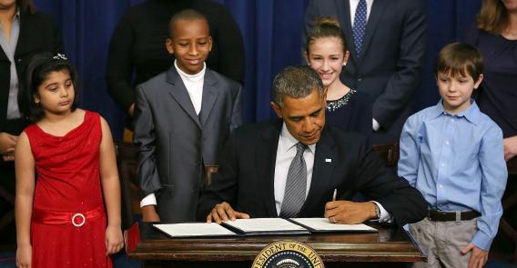 U.S. President Barack Obama signs a series of executive orders about the administration's new gun law proposals as children who wrote letters to the White House about gun violence (from left) Hinna Zeejah, Taejah Goode, Julia Stokes, and Grant Fritz, look on, Jan. 16, 2013