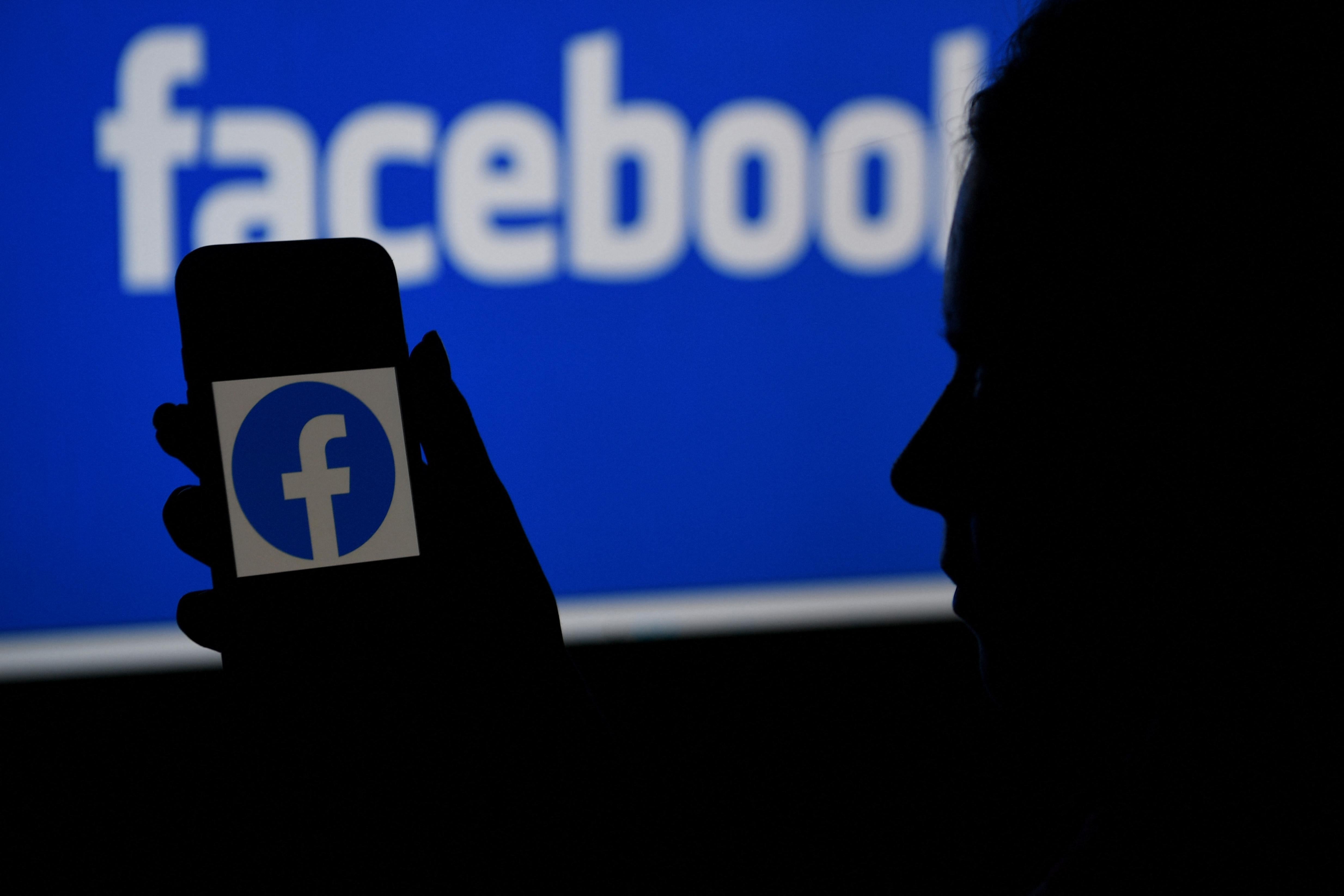 In this photo illustration, a smart phone screen displays the logo of Facebook on a Facebook website background, on April 7, 2021, in Arlington, Virginia - Facebook usage has held steady in the United States despite a string of controversies about the leading social network, even as younger users tap into rival platforms such as TikTok, a survey showed Wednesday. (Photo by OLIVIER DOULIERY / AFP) (Photo by OLIVIER DOULIERY/AFP via Getty Images)