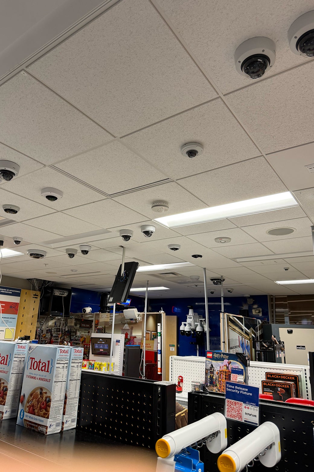 A grocery store aisle, with many cameras hanging from the ceiling to deter shoplifting.