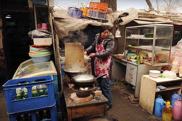 A woman cooks in an outside restaurant on a street in Beijing.