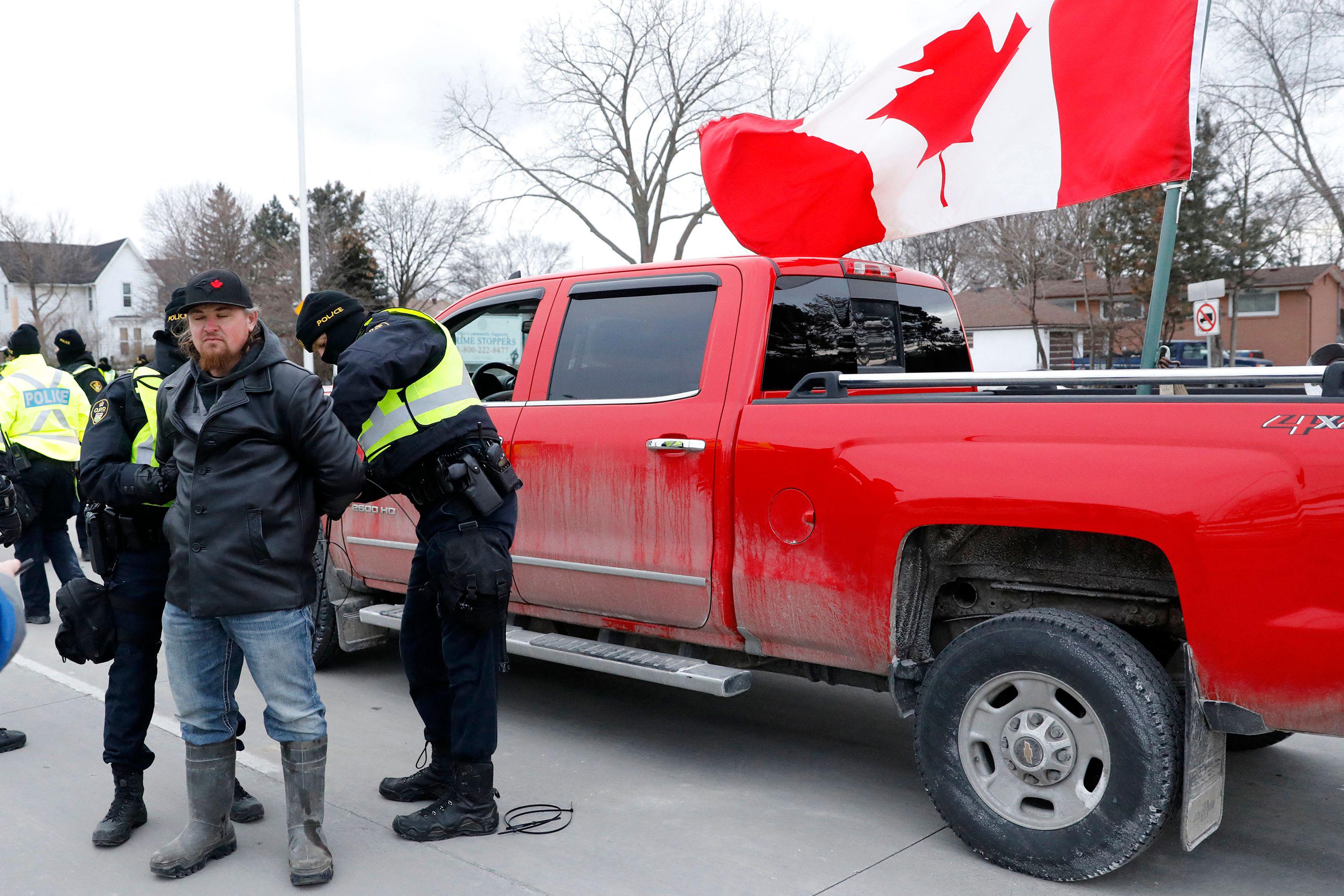 Police detain a protester as they clear demonstrators against COVID-19 vaccine mandates who blocked the entrance to the Ambassador Bridge in Windsor, Ontario, Canada, on February 13, 2022.