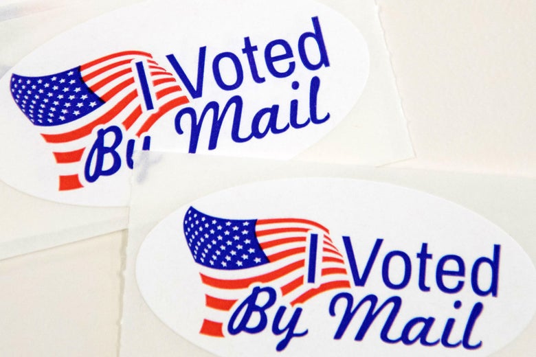 Stickers that read "I Voted By Mail" sit on a table.