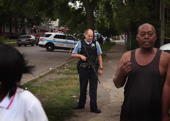 A police officer guards a crime scene where seven people were shot on July 6, 2013, in Chicago.