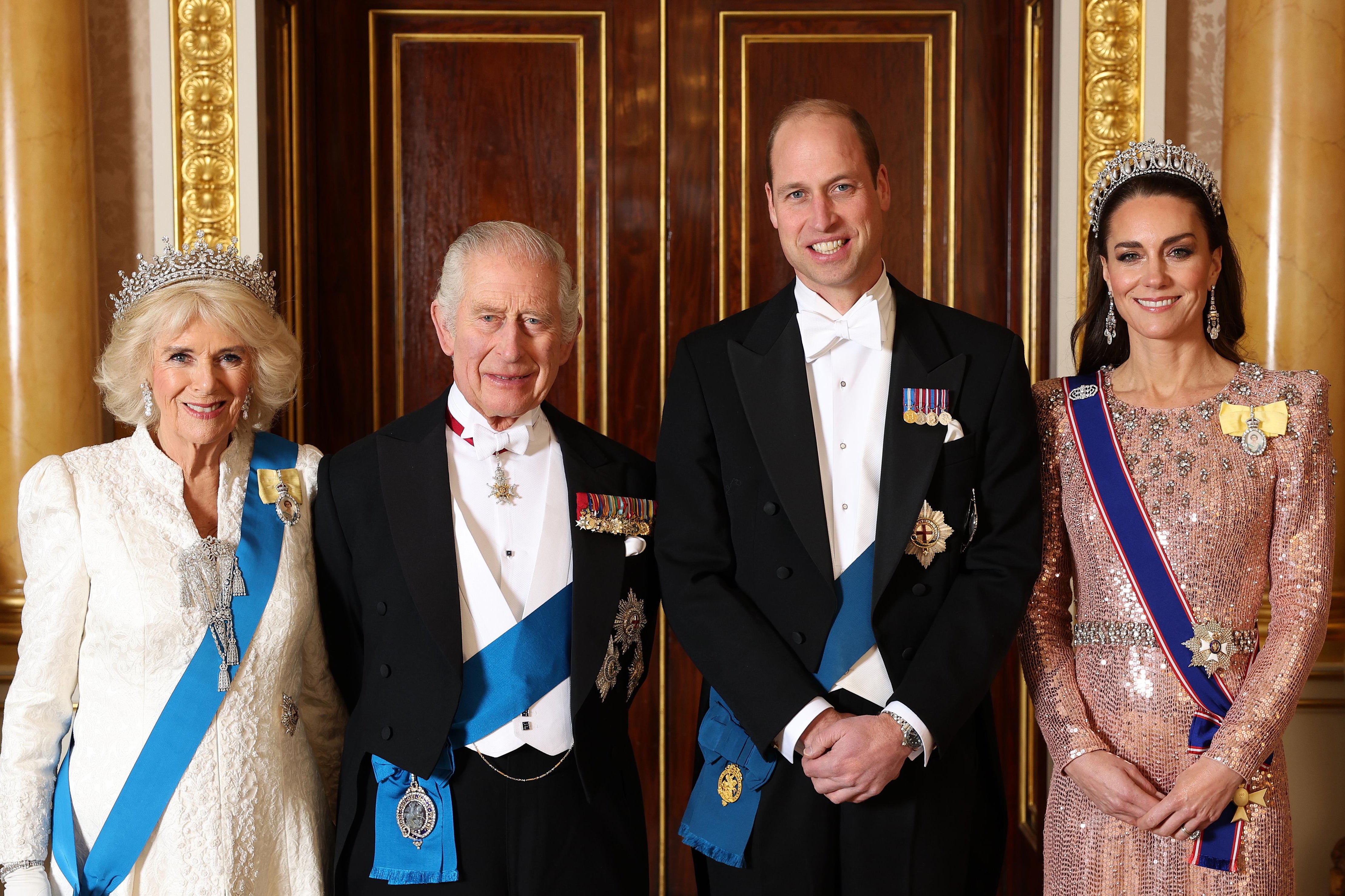 Queen Camilla, King Charles III, Prince William, and Princess Catherine smile in ceremonial wear.
