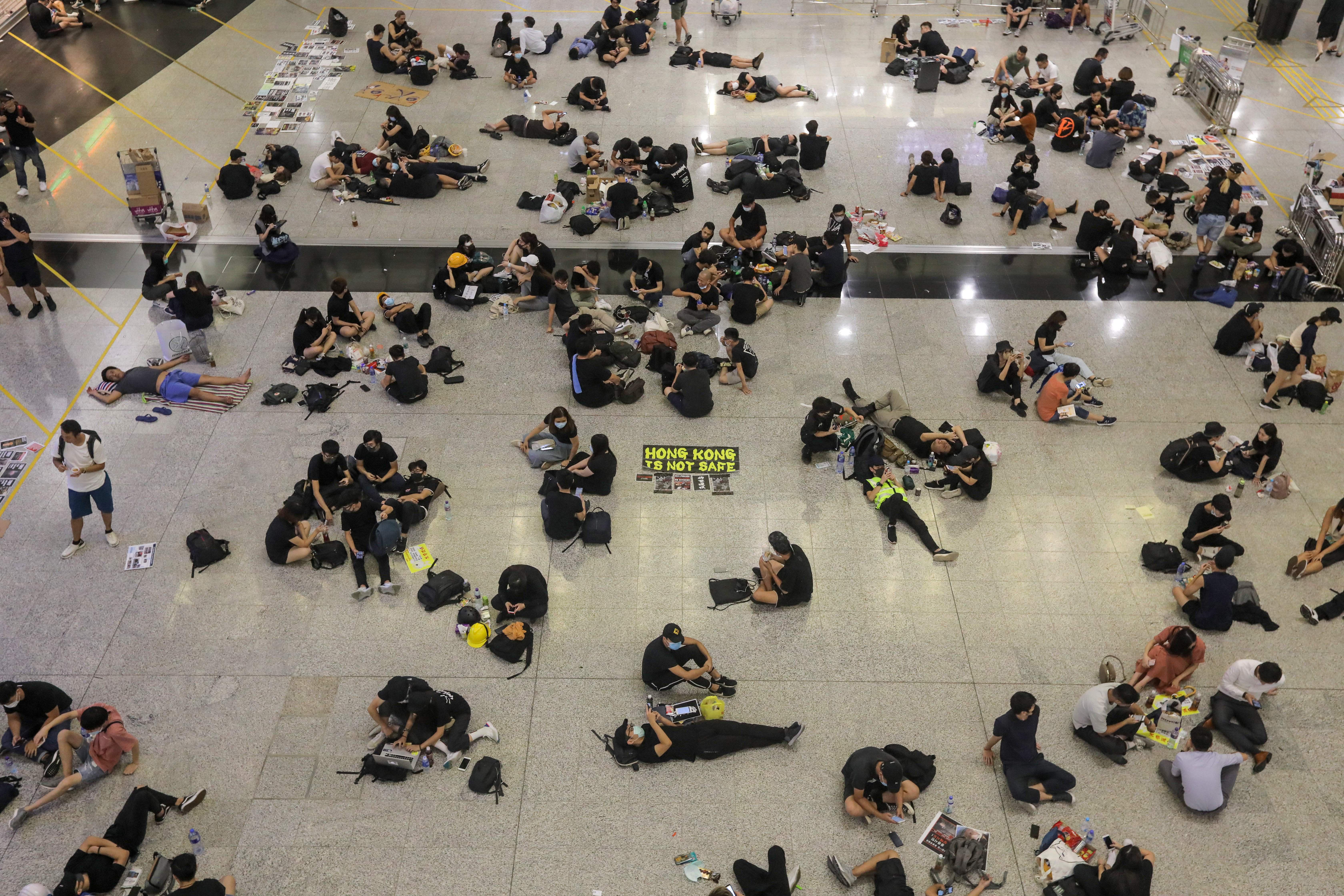 Protesters sit on the floor of the arrivals hall of the airport.