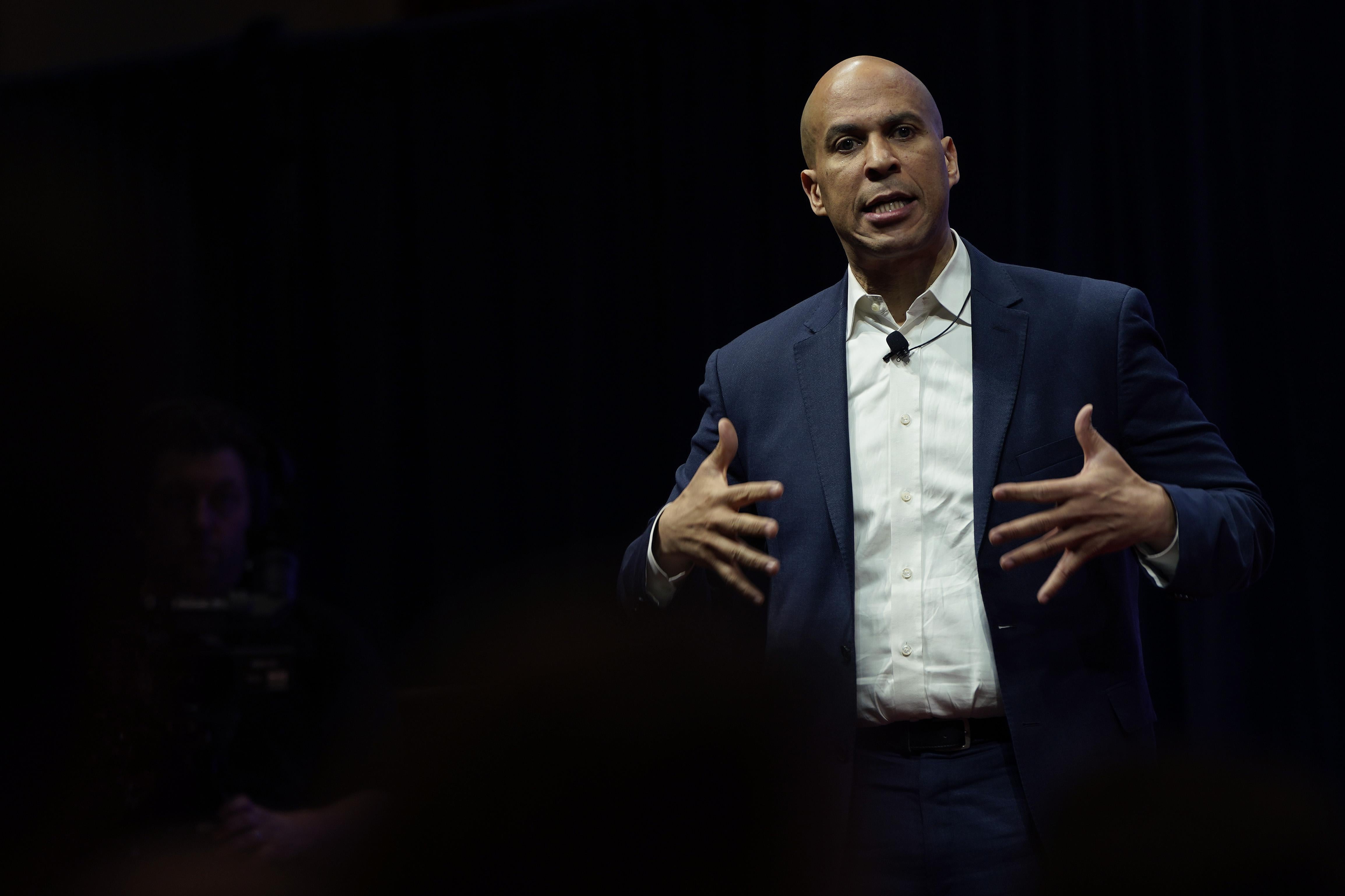 Cory Booker stretches out his fingers while speaking on a stage.