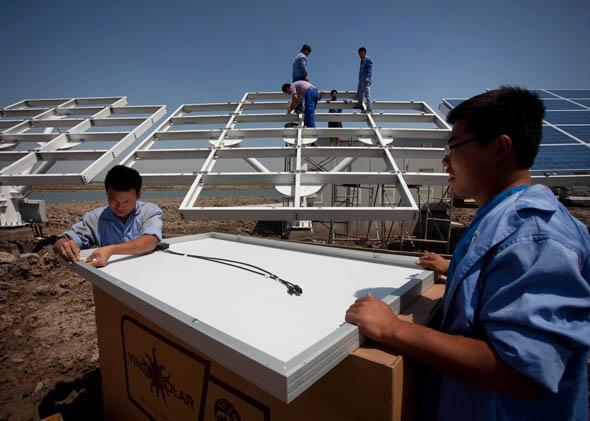 Workers install solar panels near the Sino-Singapore Eco-city near Tianjin, June 11, 2012. 