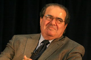 The late Justice Antonin Scalia smirking and leaning his head to the side.