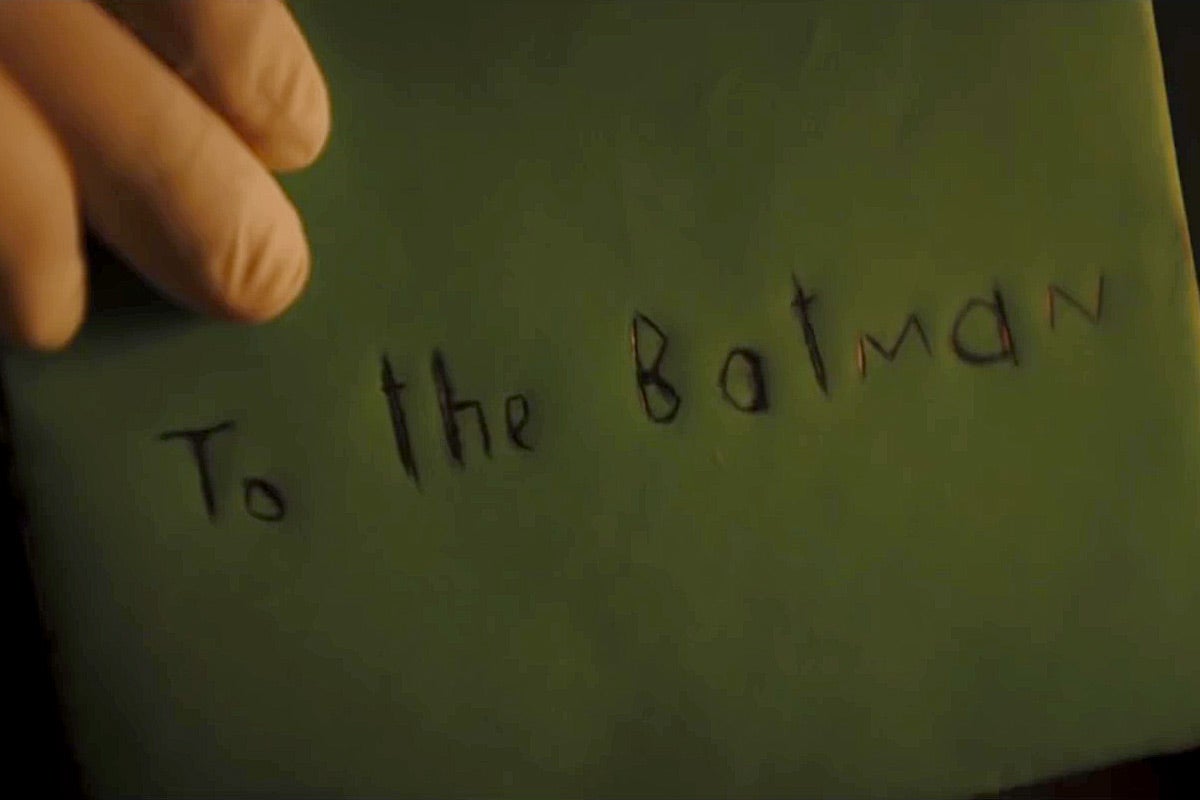 A hand in a rubber glove holds up a greeting card envelope with "To the Batman" scrawled on it.