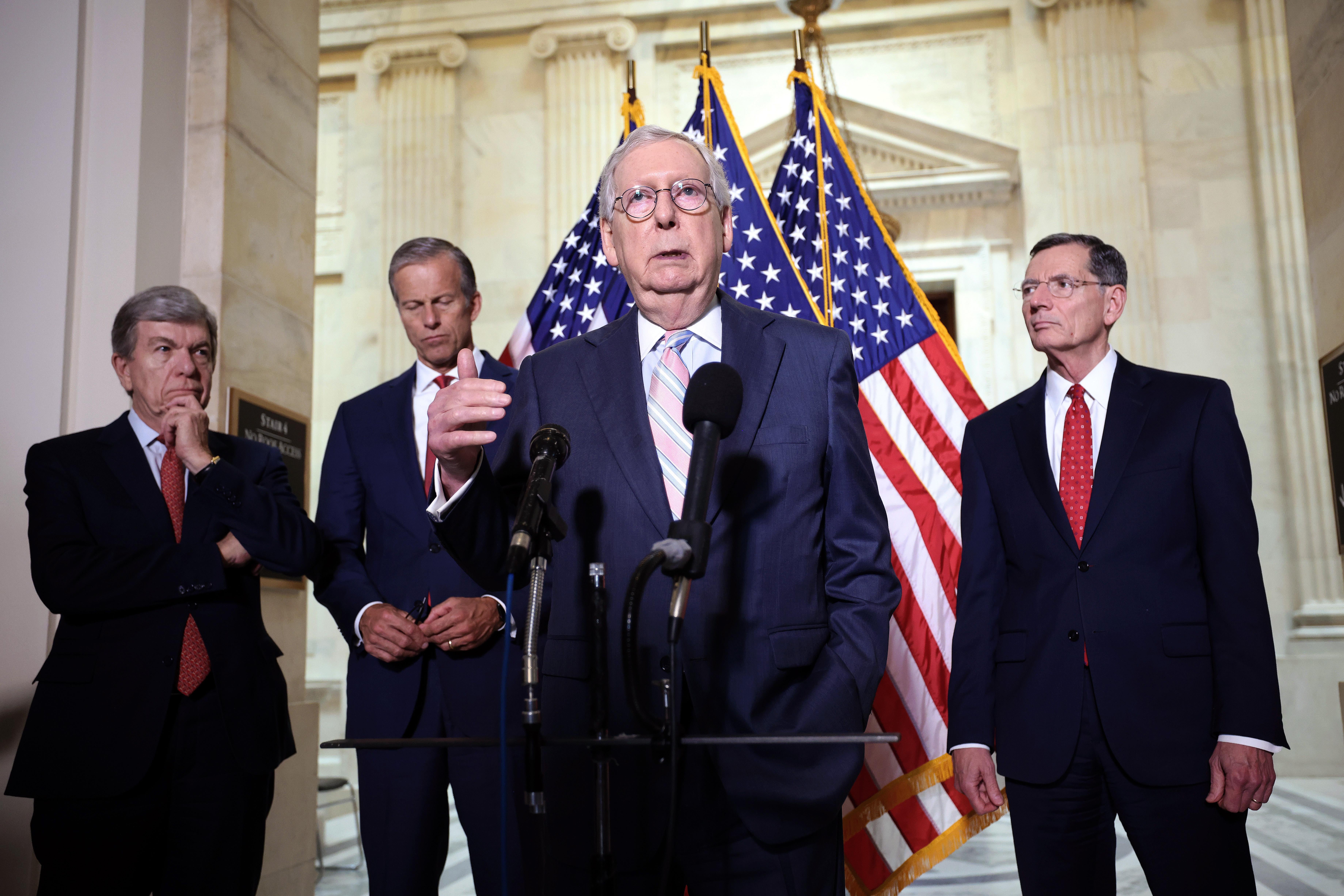 Mitch McConnell speaks at a mic with three other Republicans behind him