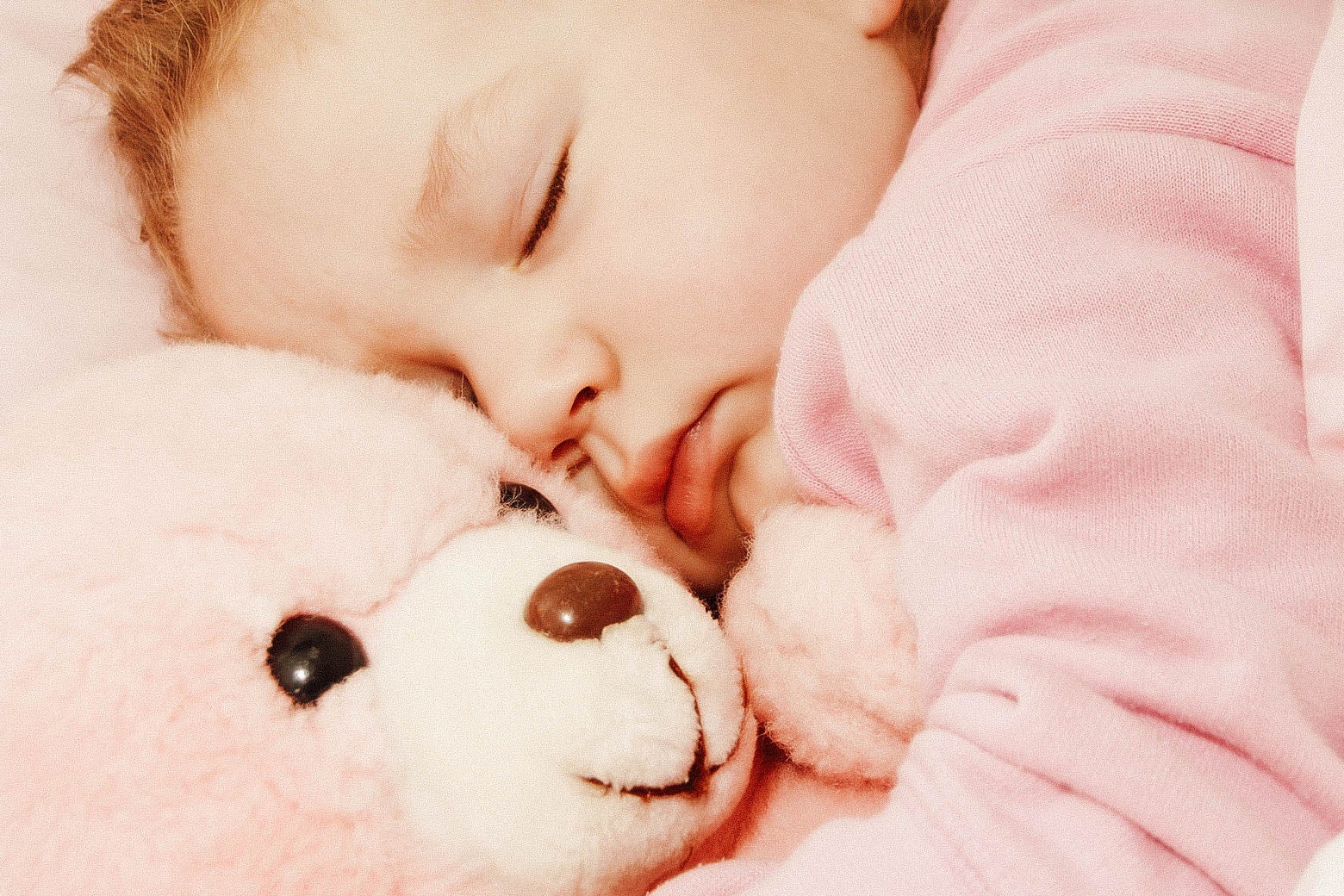 A child in bed with a teddy bear.