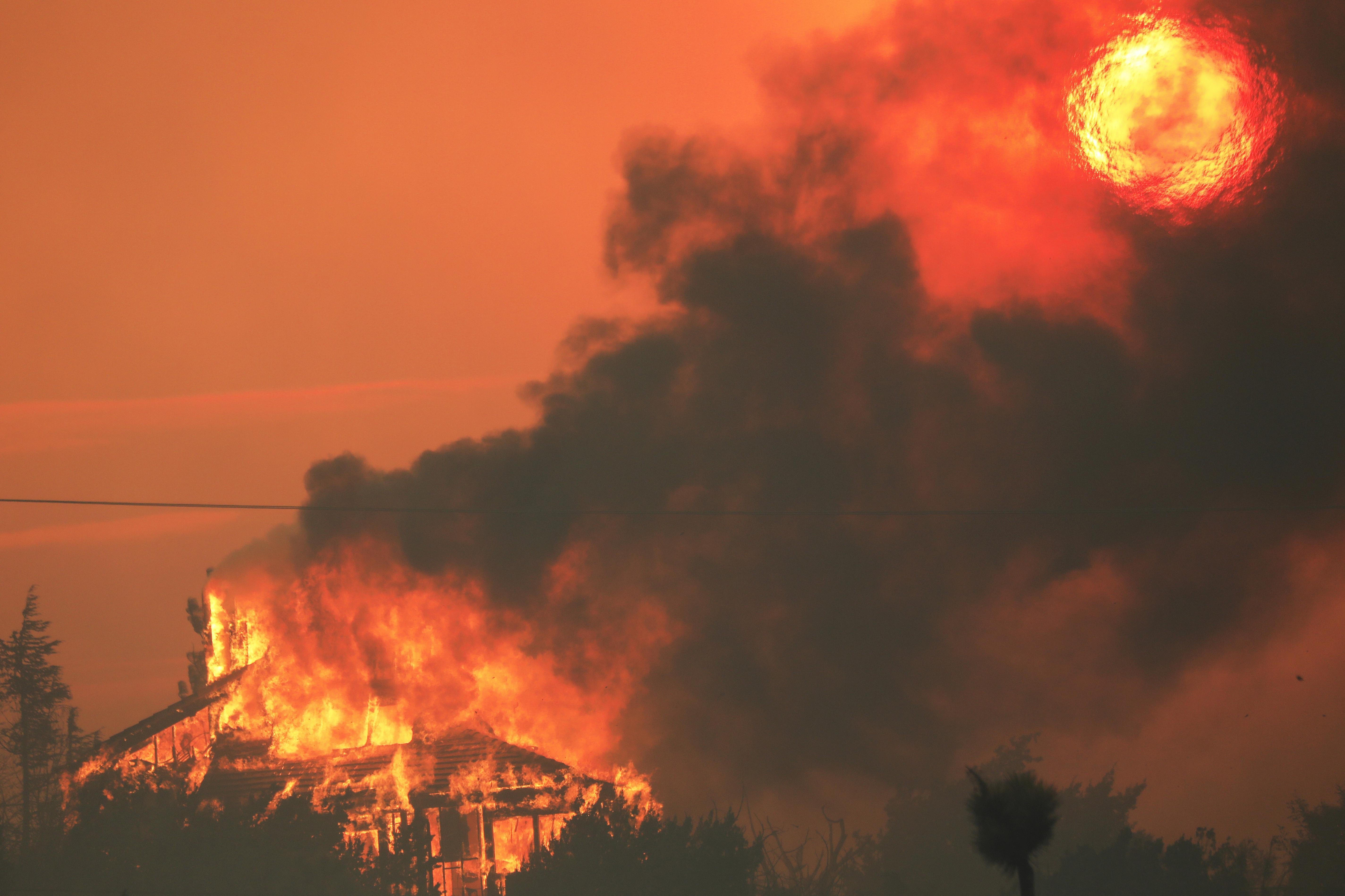 A home is seen burning as black smoke drifts toward the sky.