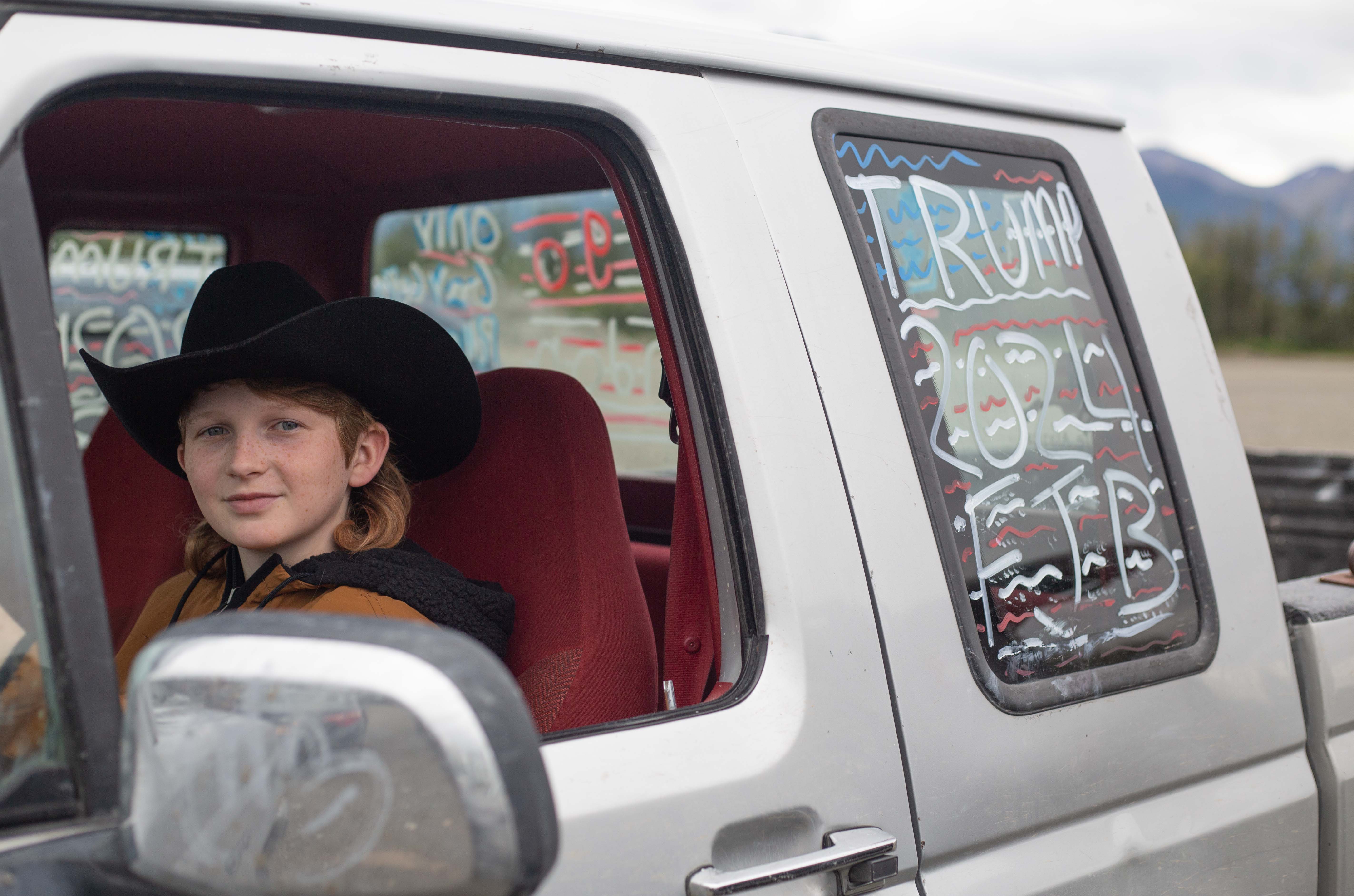 Young Alaskan boy in the drivers seat of a truck with "Trump 2024" written on the back window.