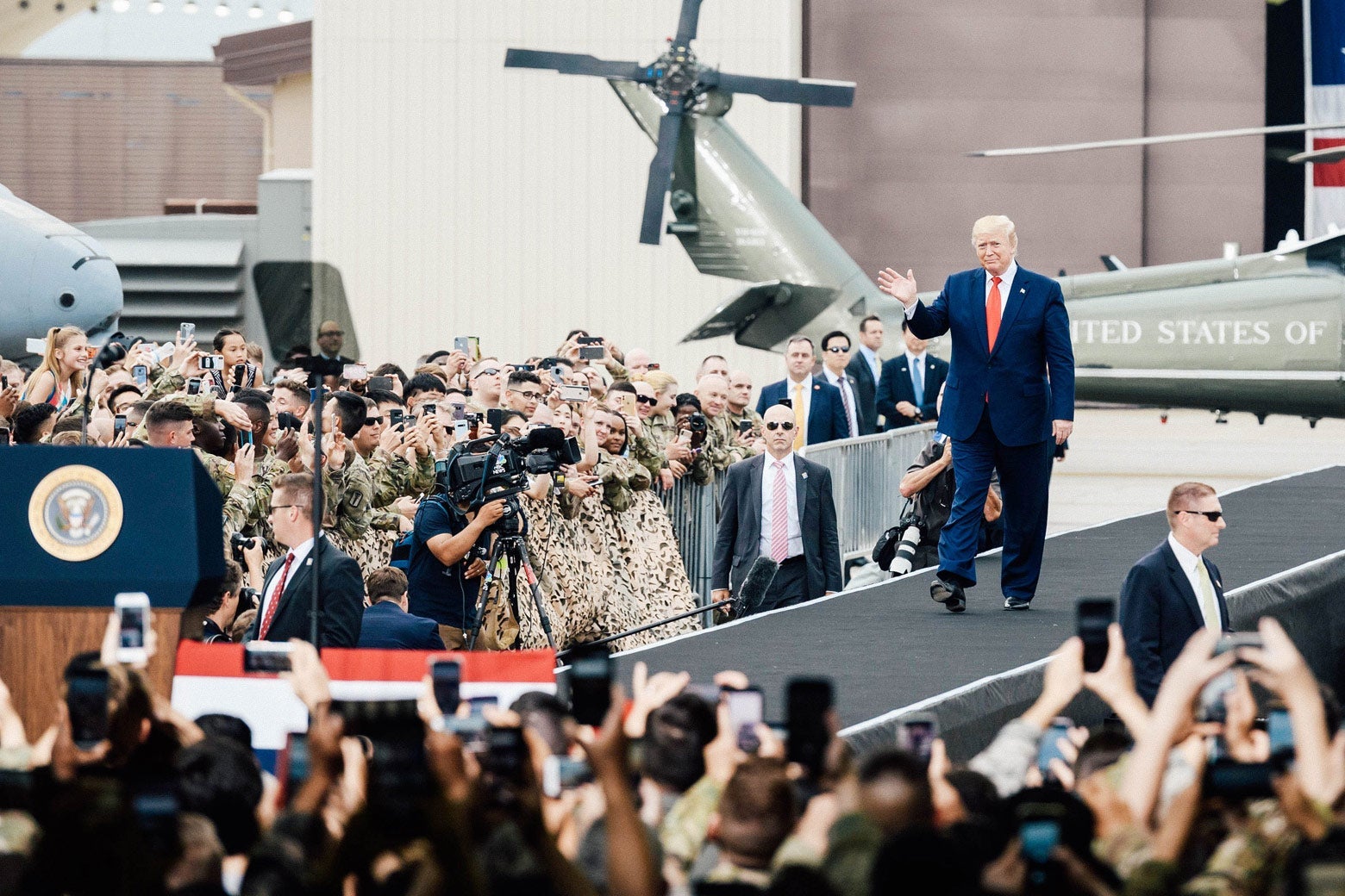 President Donald Trump waves to a crowd of troops and families.