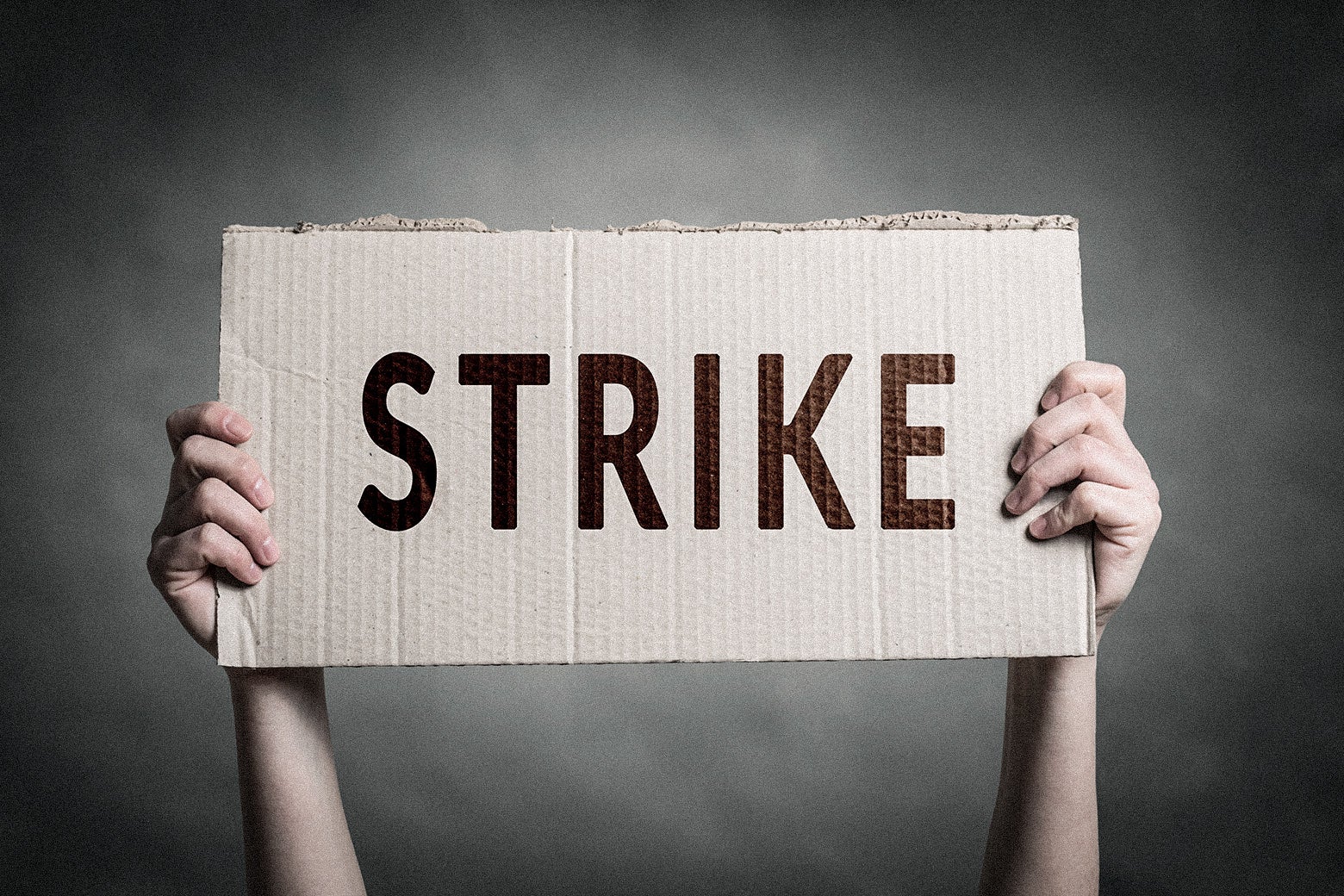 Two hands hold up a sign that simply says "Strike."