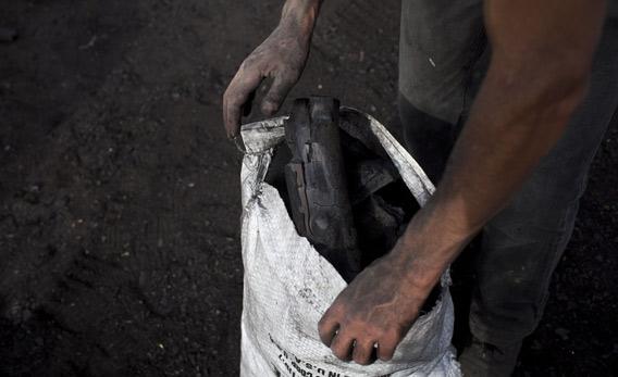Laborers prepare charcoal.