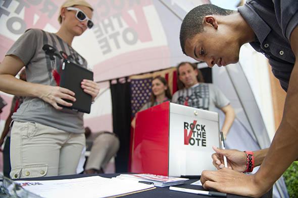 College sophomore, Denzel Fleming, signs a voting pledge during a Rock the Vote.