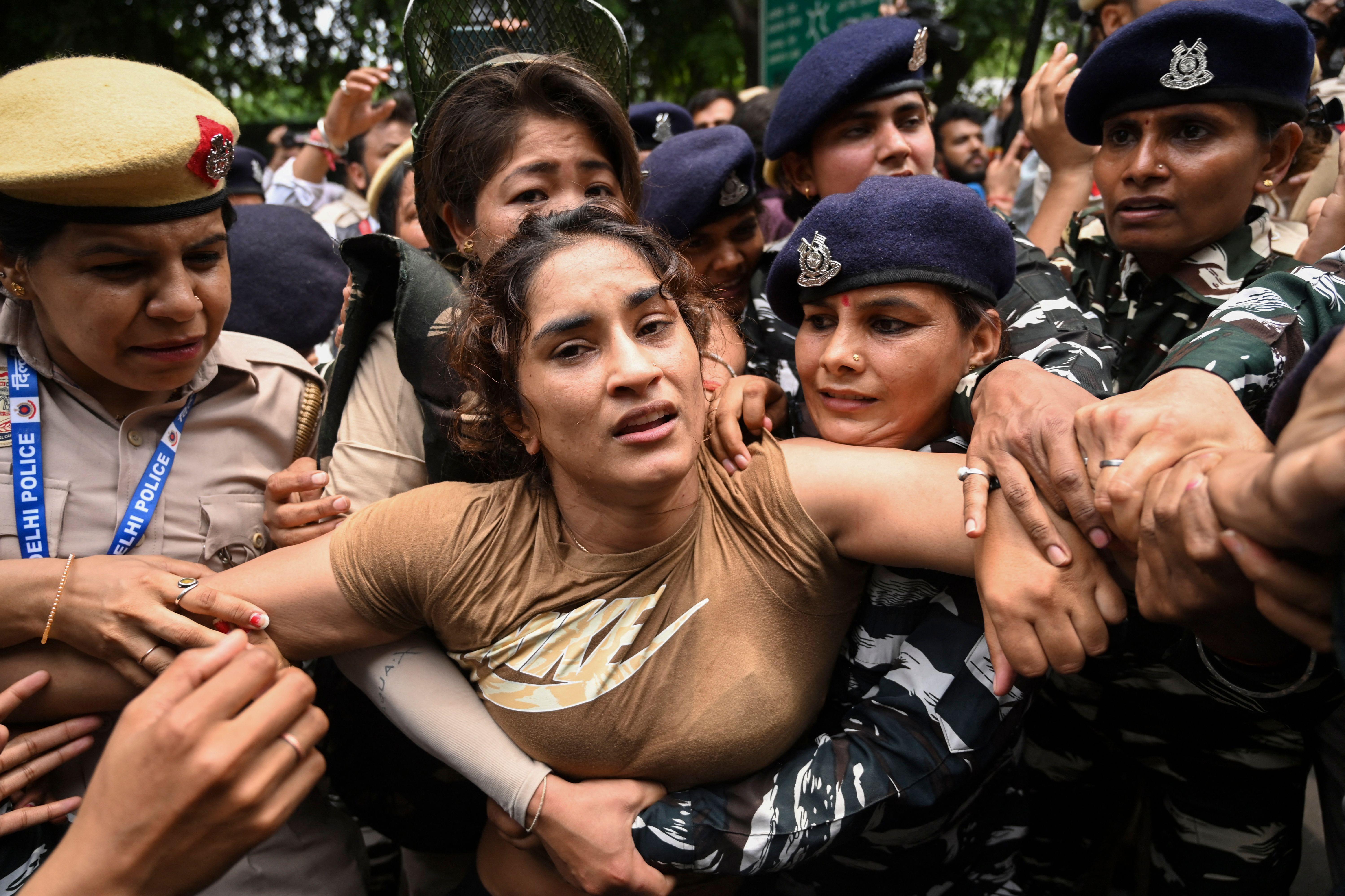 Vinesh Phogat being detained by a swarm of police officers.